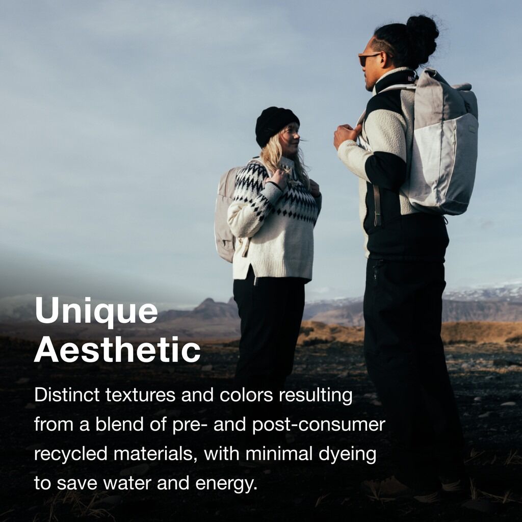 The image features two people standing outdoors in a rugged landscape with mountains and a cloudy sky in the background. They are wearing winter clothing. The person on the left wears a light sweater with a black and white pattern, a black beanie, and a l