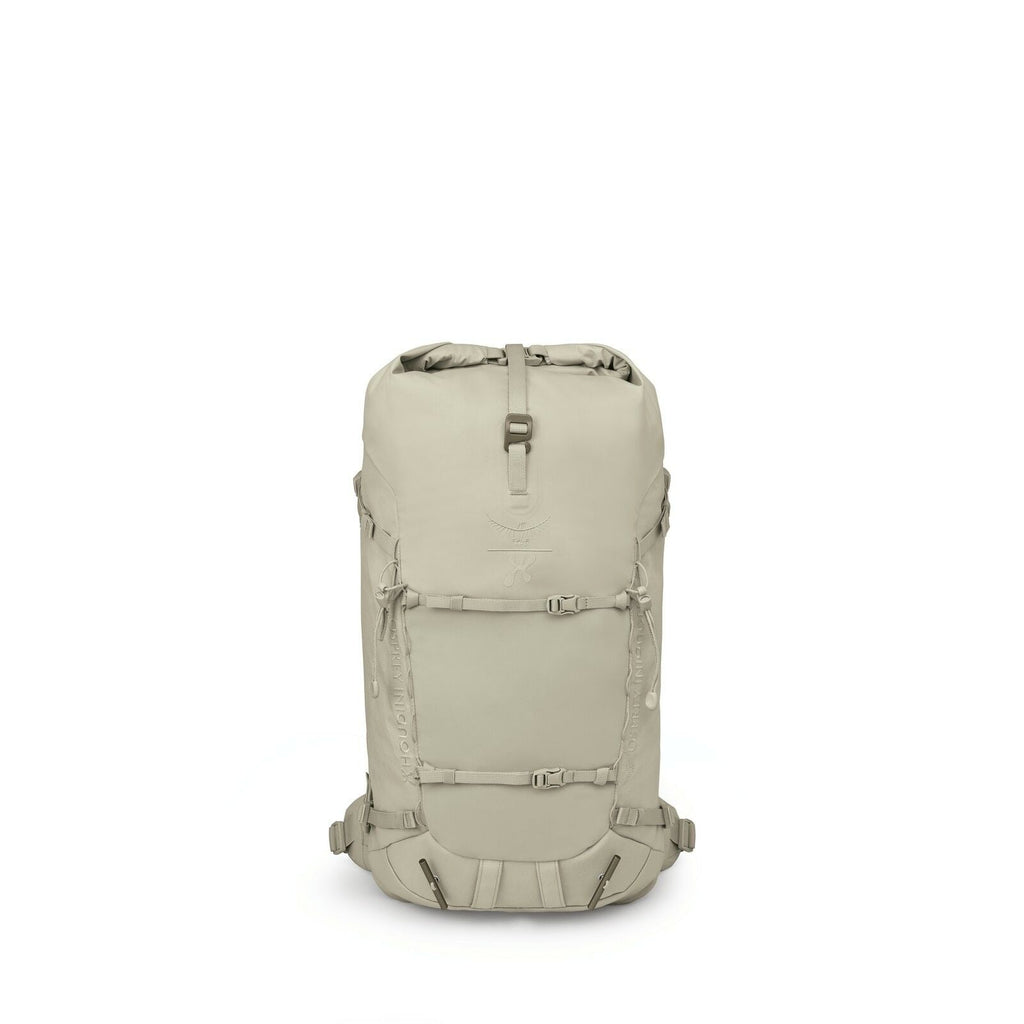 The images depict a sleek, monochromatic backpack with a minimalist design. The backpack is primarily beige in color and features a top-loading compartment with a roll-top closure secured by a buckle. On the front, there are adjustable straps, possibly fo