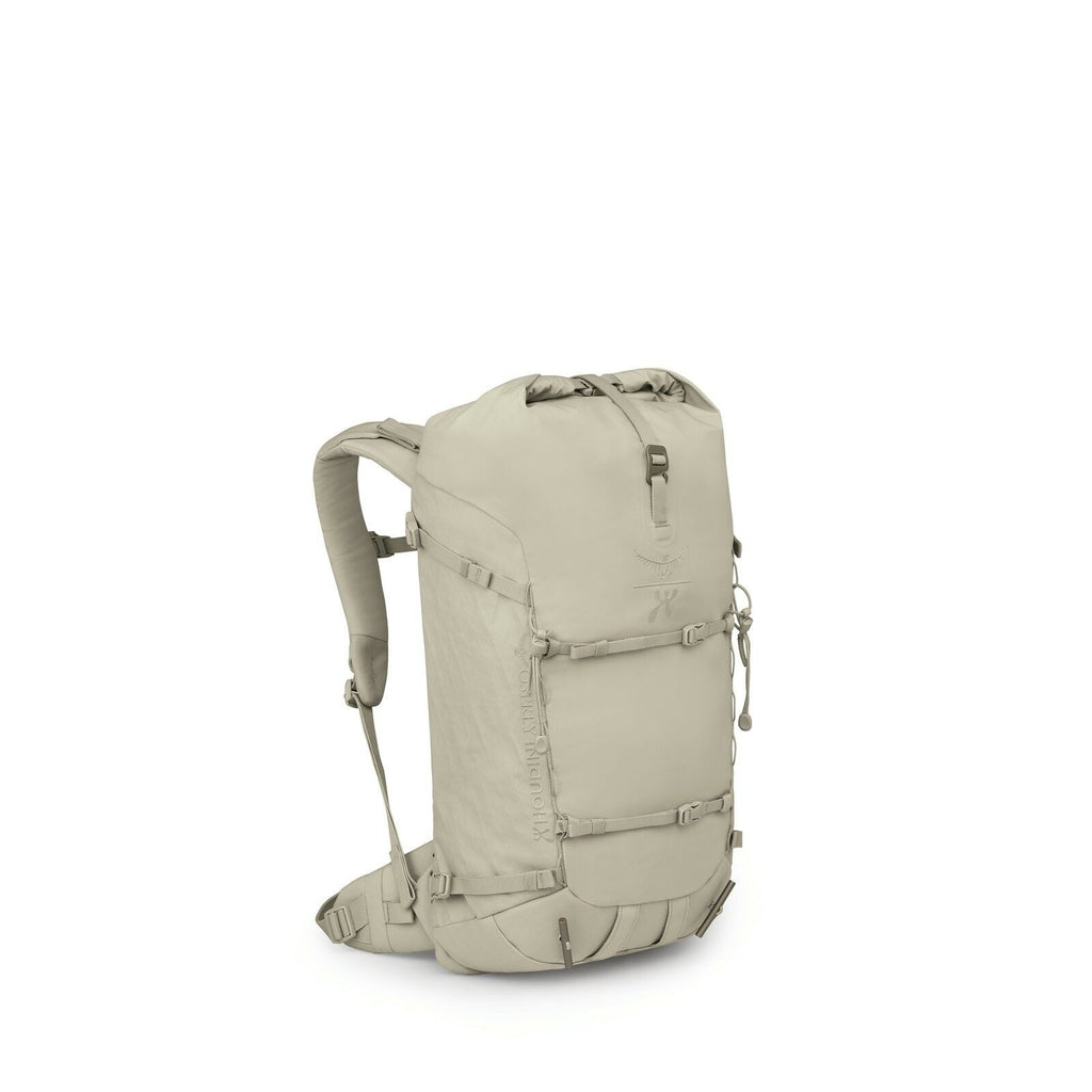 The image features a khaki-colored hiking backpack with a sleek and compact design. The bag has a roll-top closure and multiple straps and buckles for securing and adjusting the load. There are two visible side pockets, likely for storing water bottles or