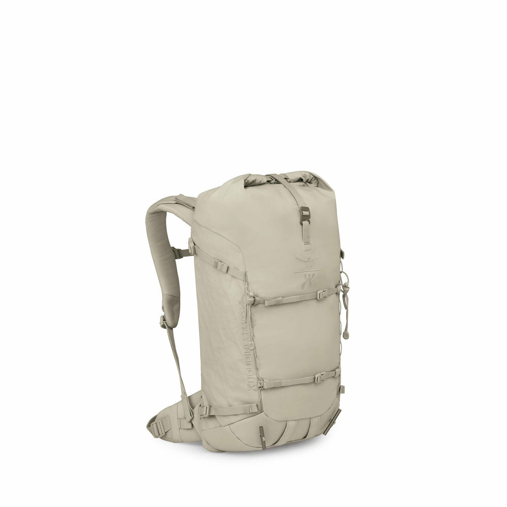 The image features a khaki-colored hiking backpack with a sleek and compact design. The bag has a roll-top closure and multiple straps and buckles for securing and adjusting the load. There are two visible side pockets, likely for storing water bottles or