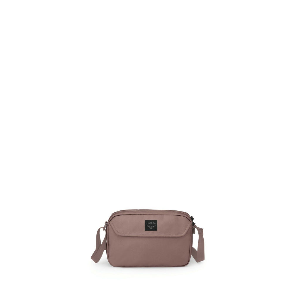 The image features a small, compact shoulder bag in a muted mauve color. The bag has a simple, rectangular shape with rounded edges and a single front pocket. It appears to be made of a smooth fabric, with a subtle sheen, and has a fabric strap for carryi