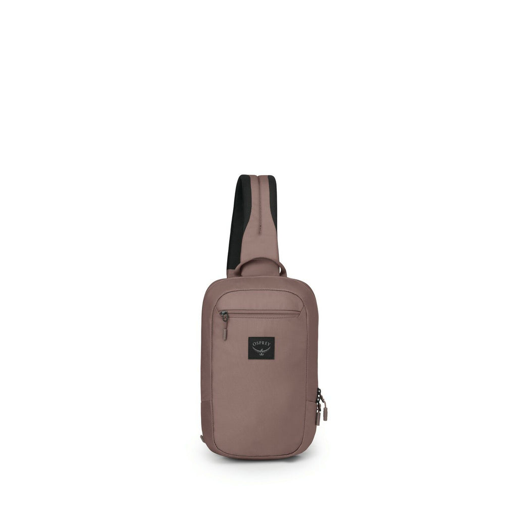The image depicts a sleek, compact crossbody sling bag in a muted brown color. The bag features a single strap for easy carrying across the body, and it is designed to be worn on the back or front. It has a rectangular shape with a main zippered compartme