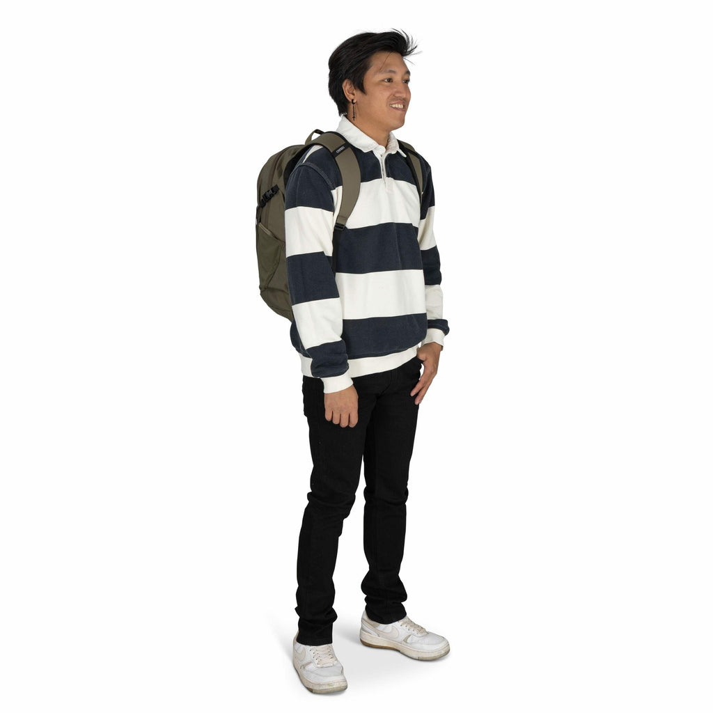 The image shows a person standing against a plain white background, dressed casually in a long-sleeve rugby-style shirt with broad horizontal stripes in navy blue and white. They are wearing slim-fitting black jeans and white sneakers, which appear slight
