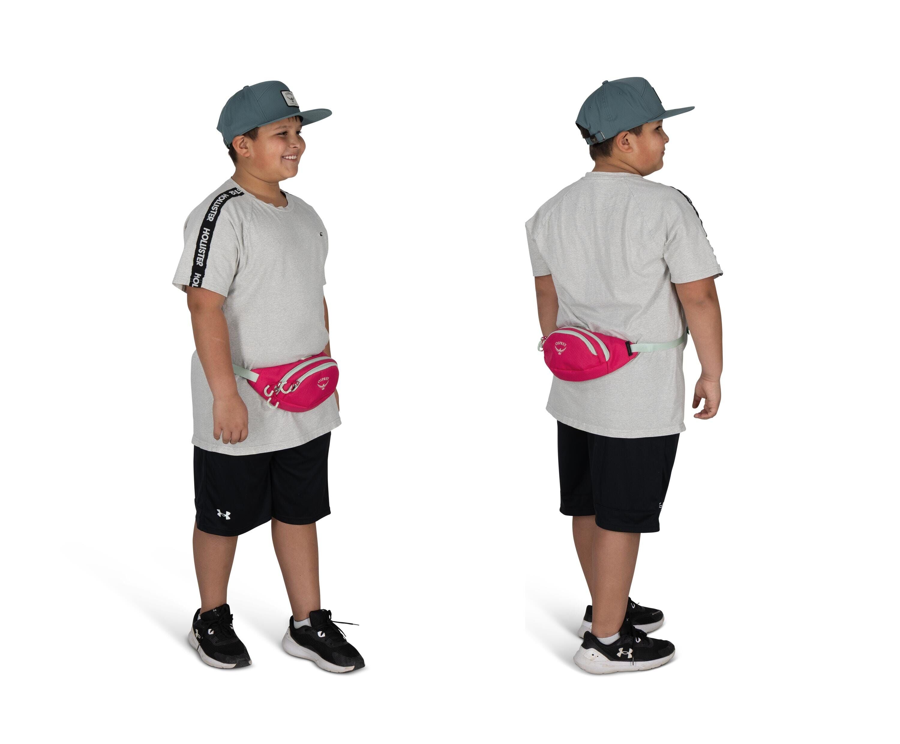 The image shows a young person standing, depicted in both a front and back view. They are wearing a light gray T-shirt with black stripes on the shoulders and black athletic shorts. A pink fanny pack is strapped around their waist. Their outfit is complet