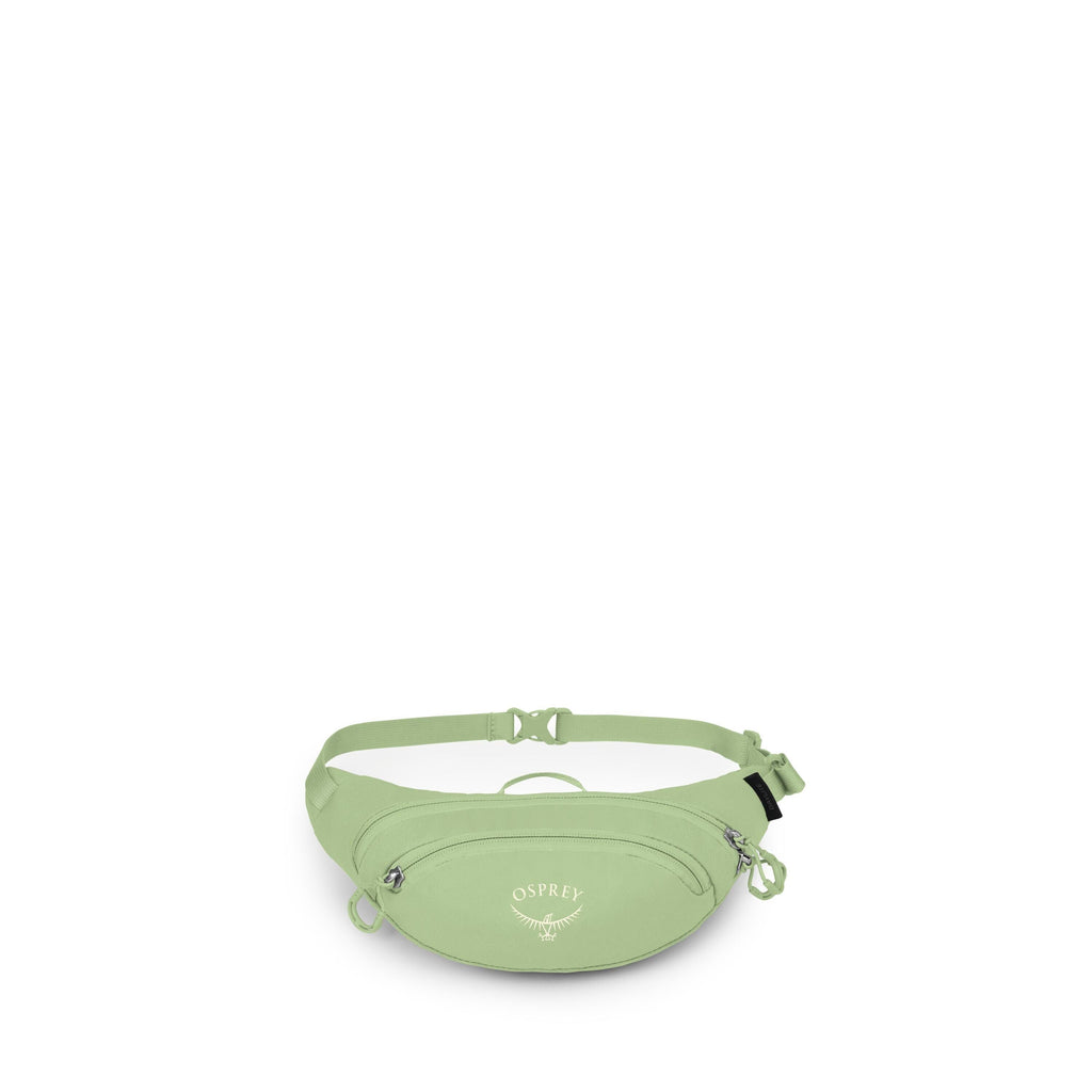 The image shows a light green Osprey waist pack, also known as a fanny pack, on a white background. It has an adjustable strap with a side-release buckle and a small top grab handle. The front features a zippered pocket with two zipper pulls and the white