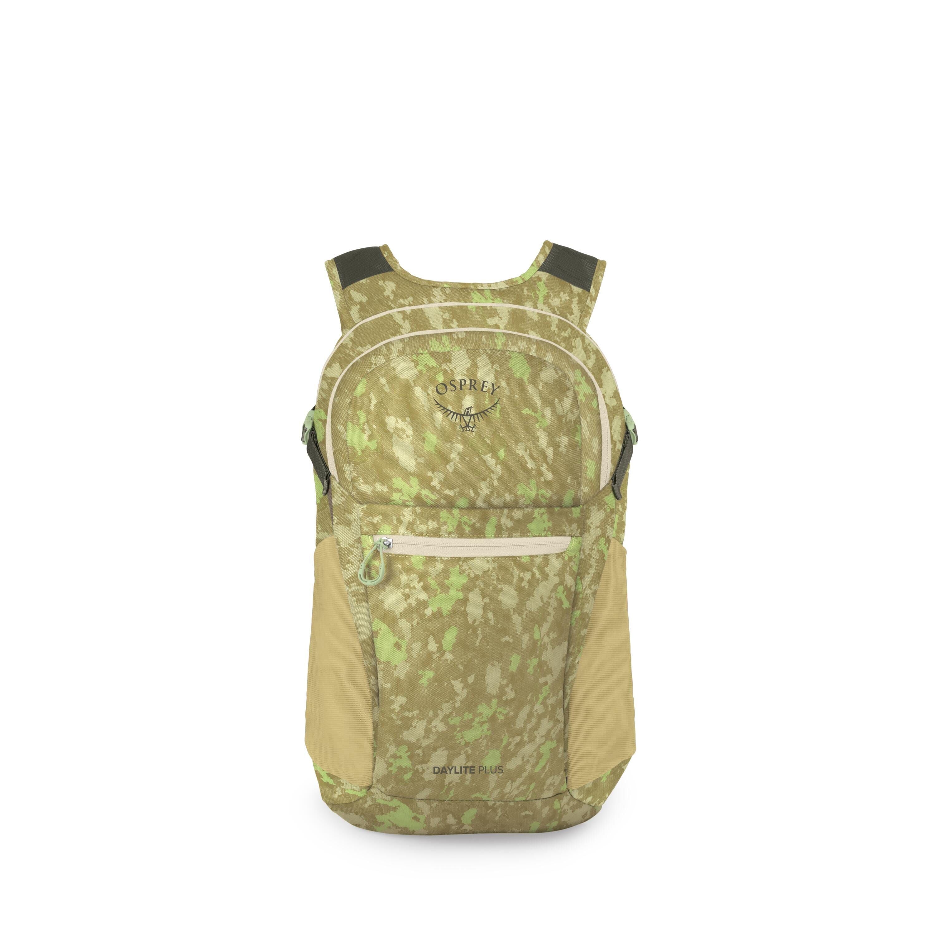 A compact Osprey backpack is shown in a front view with a green and tan digital-camo pattern. The pack features a rounded top, a large main compartment, and a front zip pocket with a light-colored zipper pull. Mesh side pockets in tan sit on both sides, a