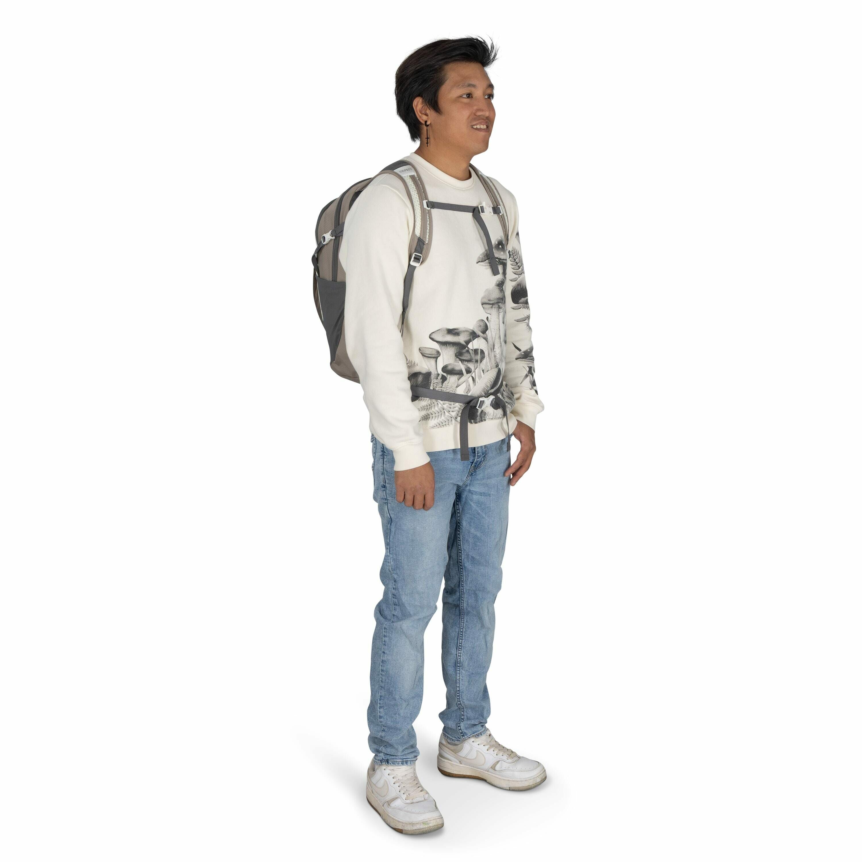 The image shows a person standing in a relaxed posture, wearing a casual outfit. They are dressed in a white sweatshirt featuring a black and white mushroom print design. The person is also wearing light blue jeans and white sneakers. Over their shoulders