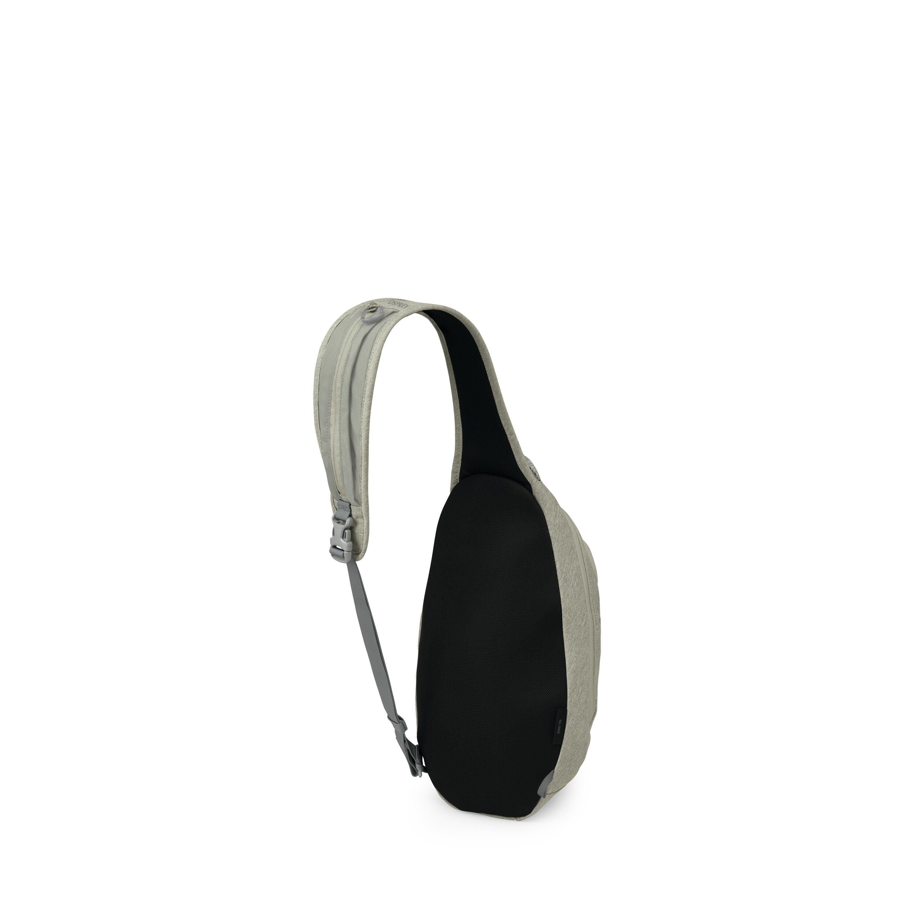 The image shows a compact sling bag with a single crossbody strap. Its front and back panel is black, while the sides and strap are a light sage or gray-green fabric. A small buckle and adjustable webbing are visible on the strap. The bag has a streamline