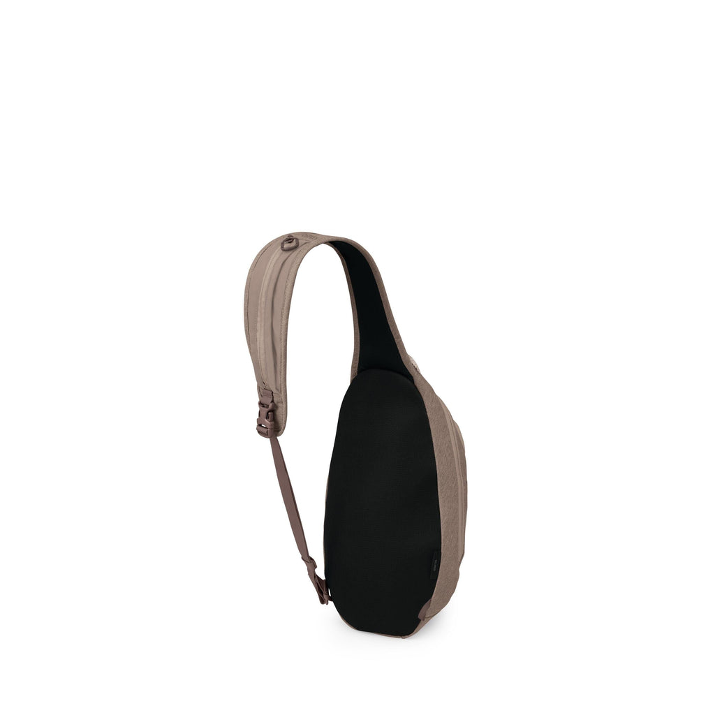 The image shows a compact sling backpack with a teardrop-shaped body. It has a single padded shoulder strap in taupe that curves over the top and connects to an adjustable brown webbing strap. The back panel is black and appears cushioned for comfort. The