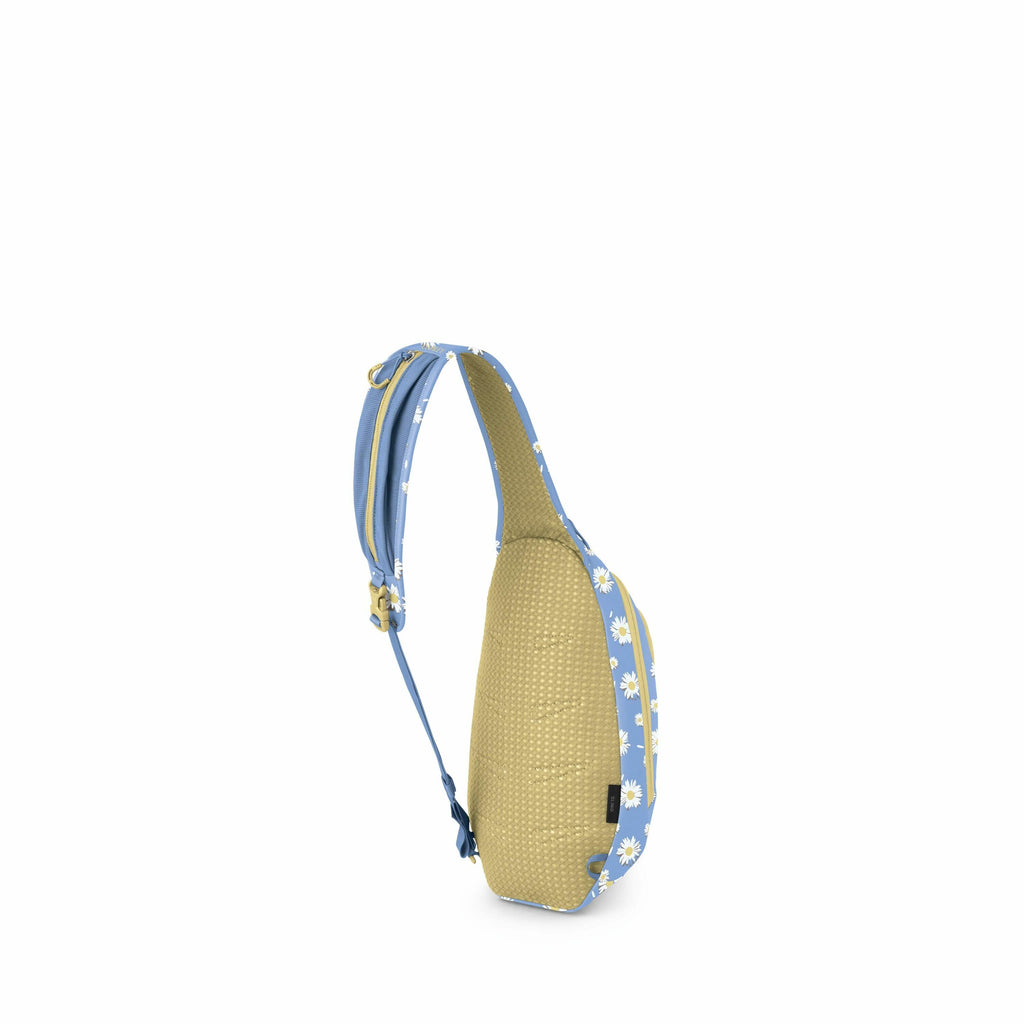 The image displays a sling backpack with a single shoulder strap design. The strap and the edges of the backpack are light blue adorned with a pattern of white daisies. The body of the backpack appears to be a beige or olive color with a subtle dotted tex