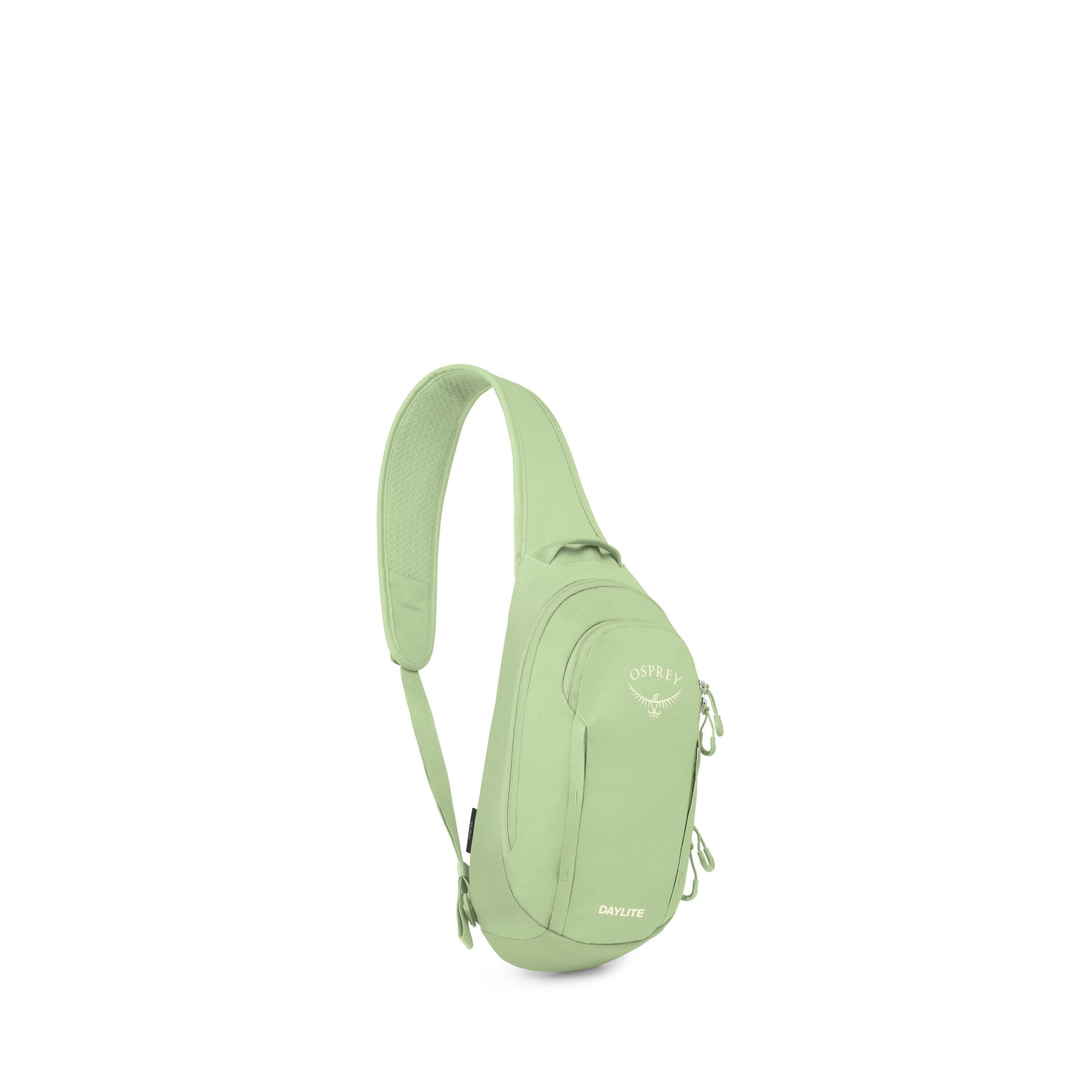 A light green Osprey Daylite sling bag is shown isolated on a white background. It has a single padded shoulder strap that crosses the body and a compact teardrop-shaped main body. The bag features multiple zippered compartments, including a front pocket