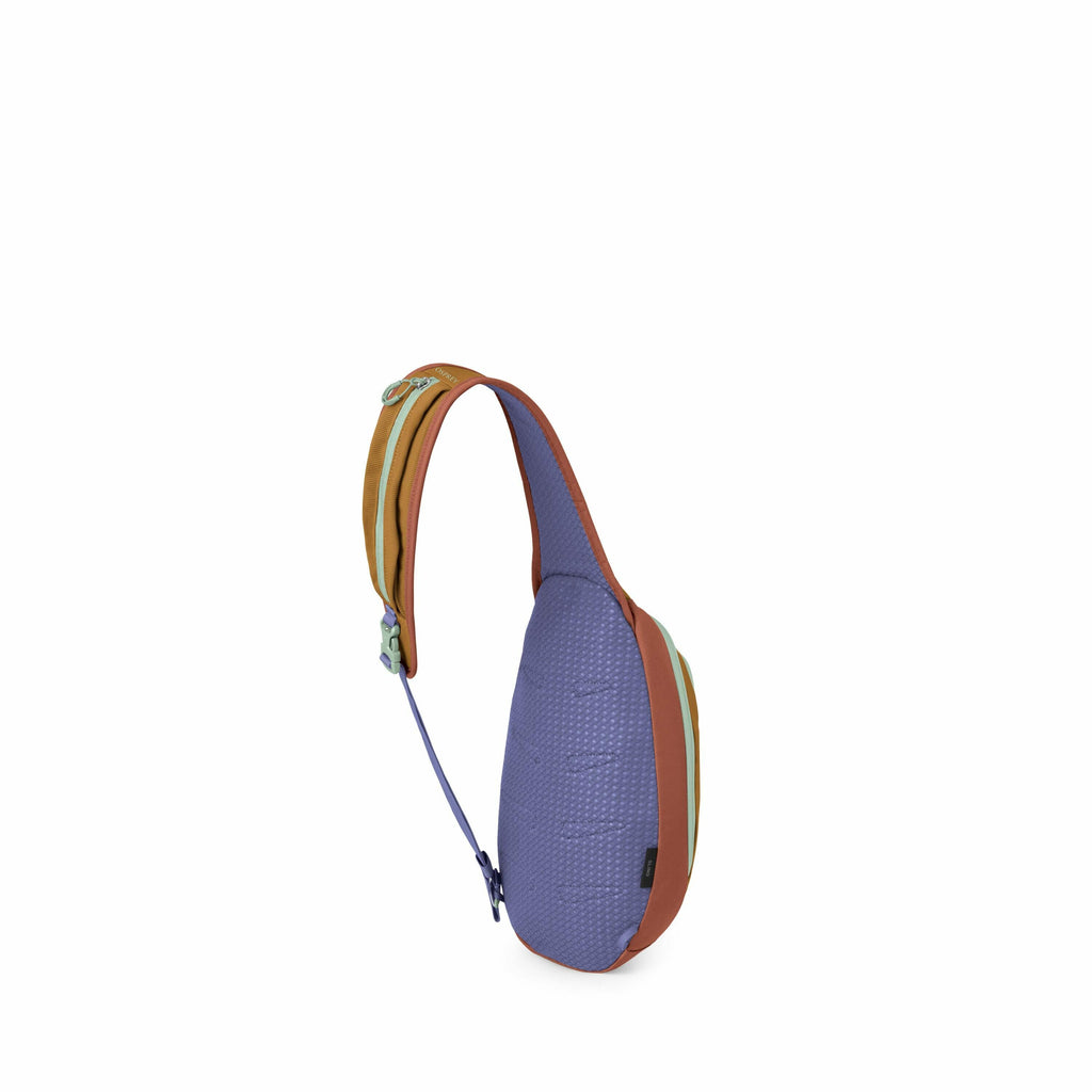 The image features a sling bag with a unique design and color scheme. The main body of the bag is a textured purple, with a red border running along the edges. The strap of the bag is a combination of brown and orange, accented with small green clips for