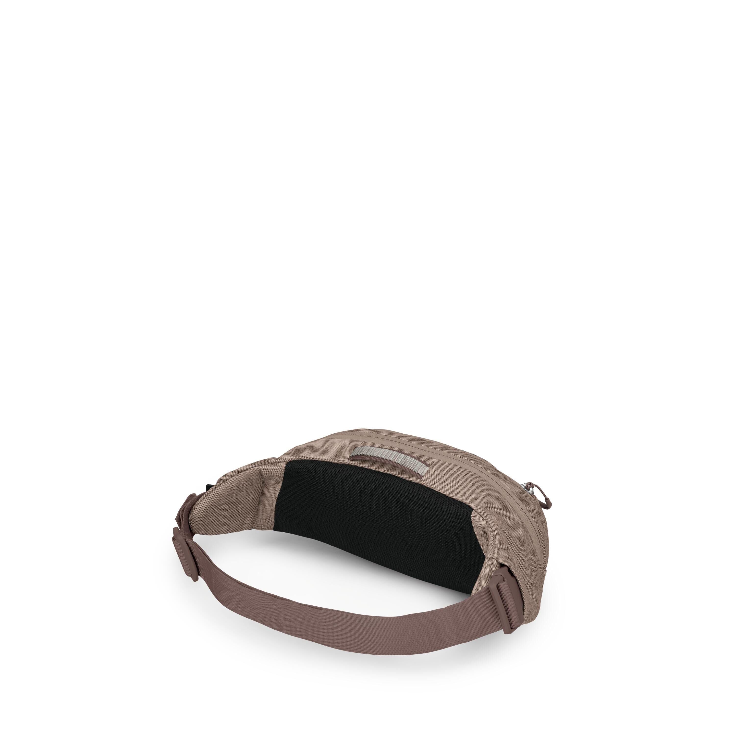 The image shows a small, minimalist waist/hip pack in a muted taupe fabric. It has a wide, adjustable mauve strap with a side-release buckle and a black padded back panel for comfort. A top zipper opens the main compartment, and a small fabric loop handle