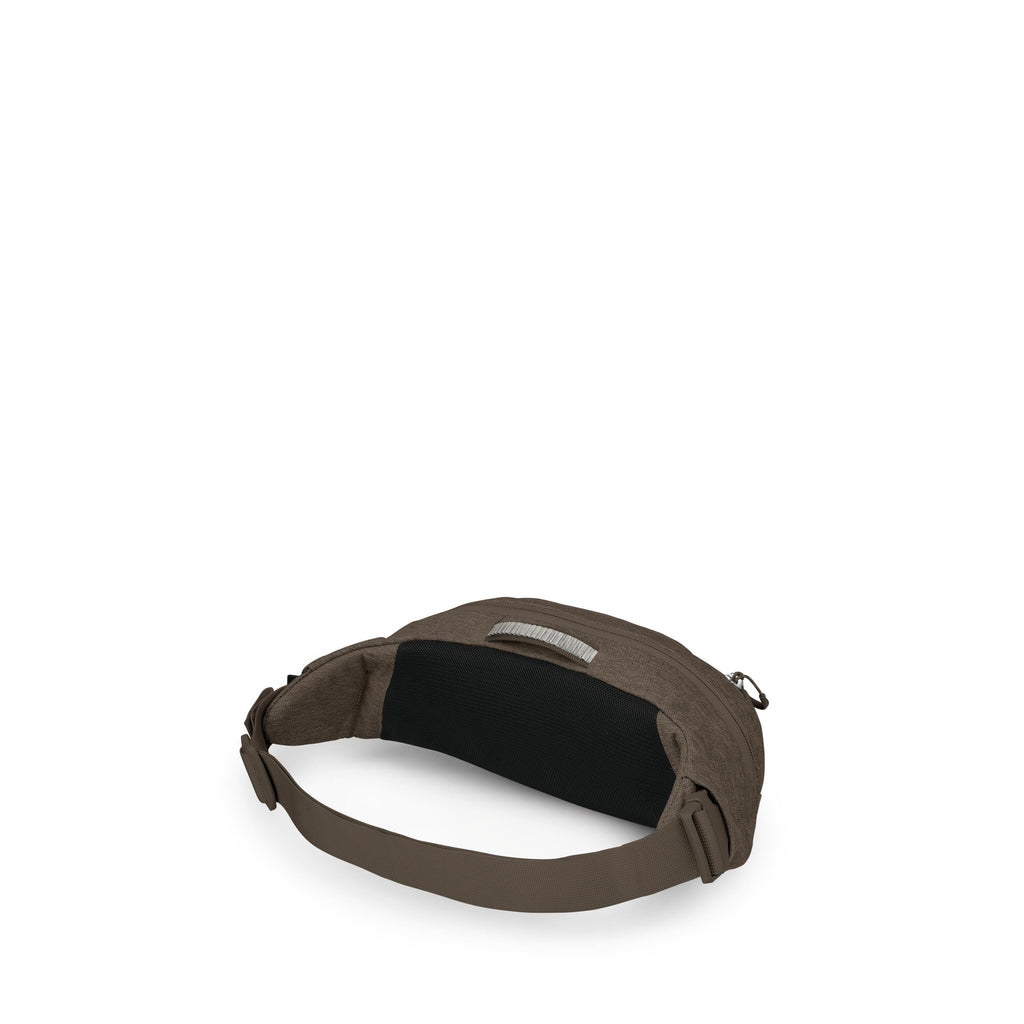 The image shows a small, minimalist waist/hip pack in a dark brown fabric. It has a wide, adjustable brown strap with a side-release buckle and a black padded back panel for comfort. A top zipper opens the main compartment, and a small fabric loop handle