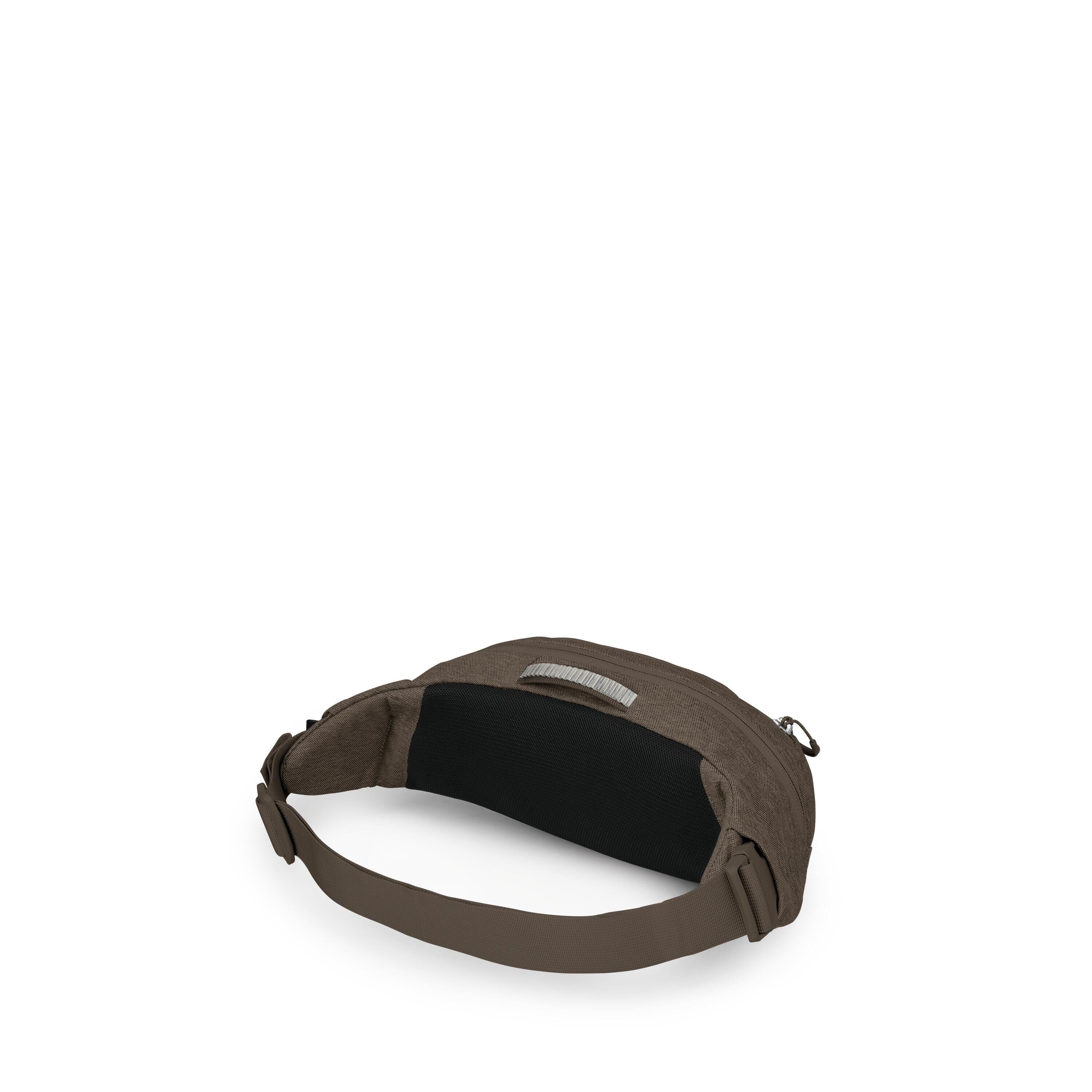 The image shows a small, minimalist waist/hip pack in a dark brown fabric. It has a wide, adjustable brown strap with a side-release buckle and a black padded back panel for comfort. A top zipper opens the main compartment, and a small fabric loop handle
