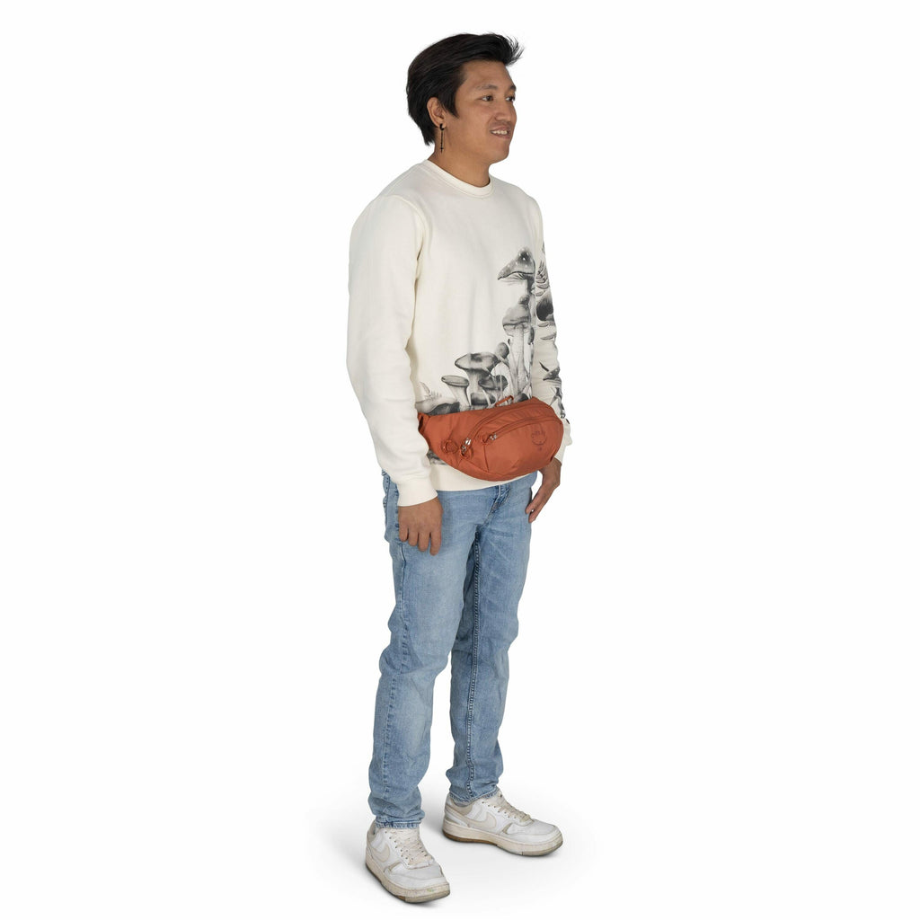 The image features a person standing in a casual pose, wearing a cream-colored sweatshirt with a large black and white floral print on it. They have on light blue jeans and white athletic sneakers, which give the outfit a laid-back and comfortable vibe. A