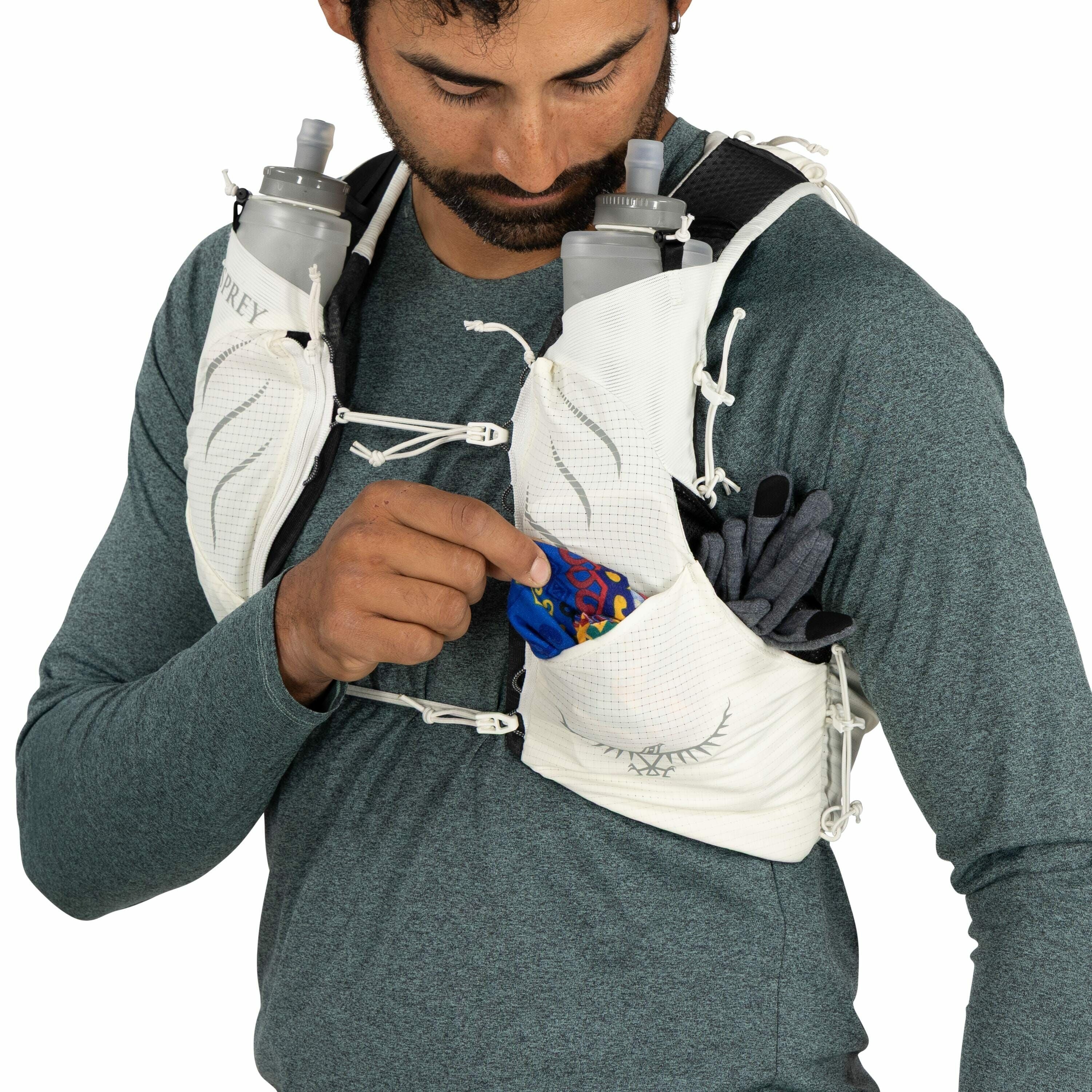 The image shows a person wearing a running hydration vest, which appears to be made by Osprey, as indicated by the logo on the vest. The vest is white with black accents and features multiple pockets designed for storing gear and essentials while running.
