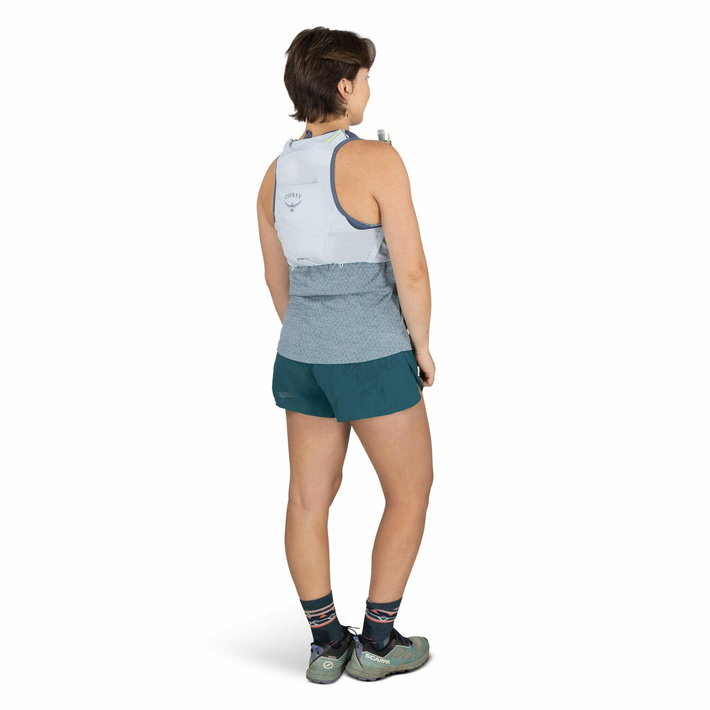 The image shows a person wearing athletic gear suitable for outdoor activities. The individual is wearing a light blue running vest with the brand "Osprey" visible on the back, over a light blue sleeveless top. They have dark teal running shorts and are e