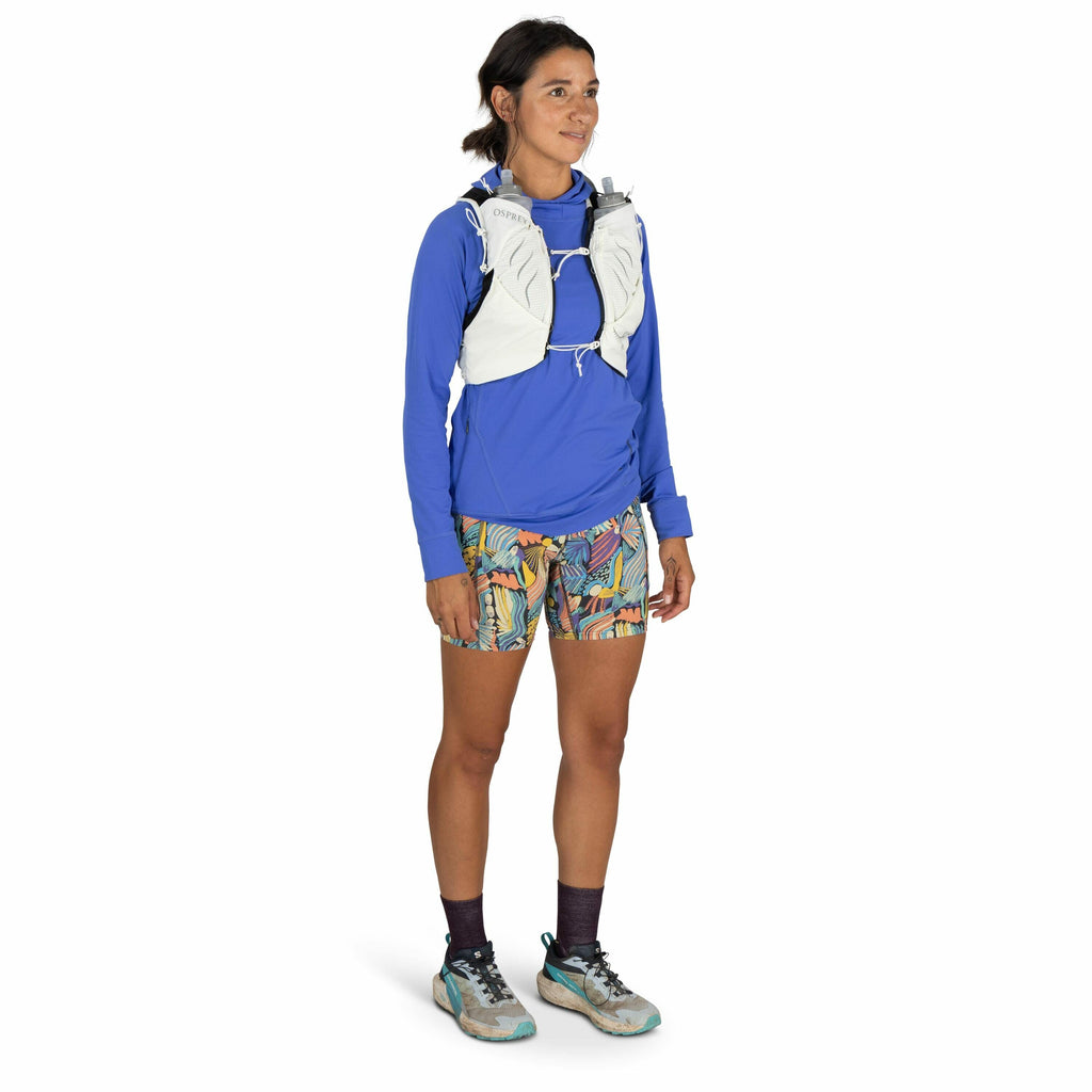 The image features a person dressed in sporty attire, suitable for outdoor activities like hiking or trail running. They are wearing a long-sleeved blue shirt paired with vibrant, multi-colored patterned shorts. On their feet are blue and white athletic s