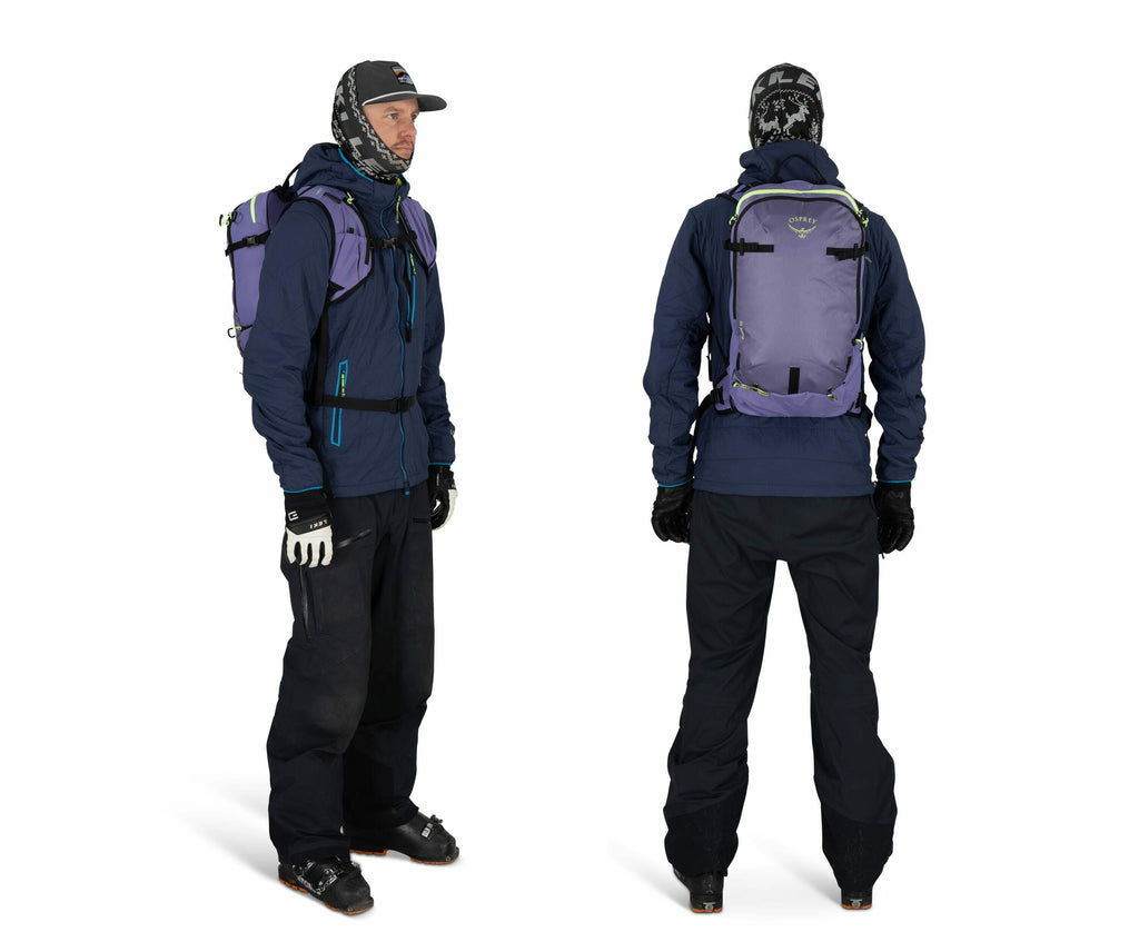The image shows a person dressed in winter gear, both from the front and the back. The individual is wearing a dark blue jacket paired with black snow pants and black gloves. On their head, they have a hat and a scarf or balaclava, providing additional wa