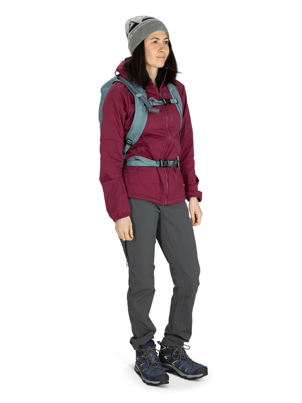 The image shows a person dressed for outdoor activities, such as hiking. They are wearing a dark maroon jacket, which appears to be insulated and weather-resistant, paired with gray pants that seem suitable for trekking or mountaineering. On their feet, t