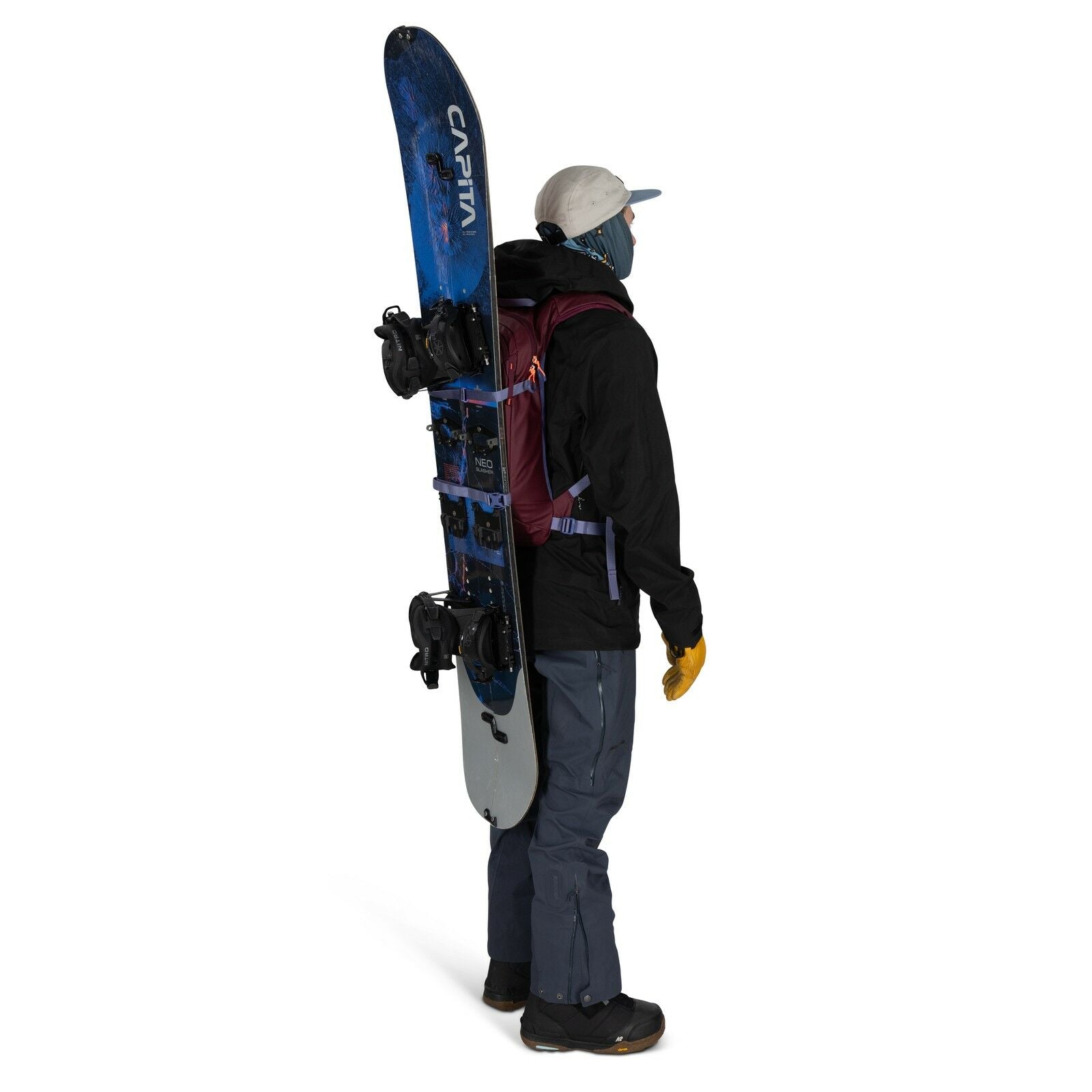 The image features a person standing in a side profile view, fully equipped for a snowboarding adventure. They are wearing a black jacket, gray pants, and yellow gloves, along with sturdy black boots, ideal for snowy conditions. A purple backpack is strap