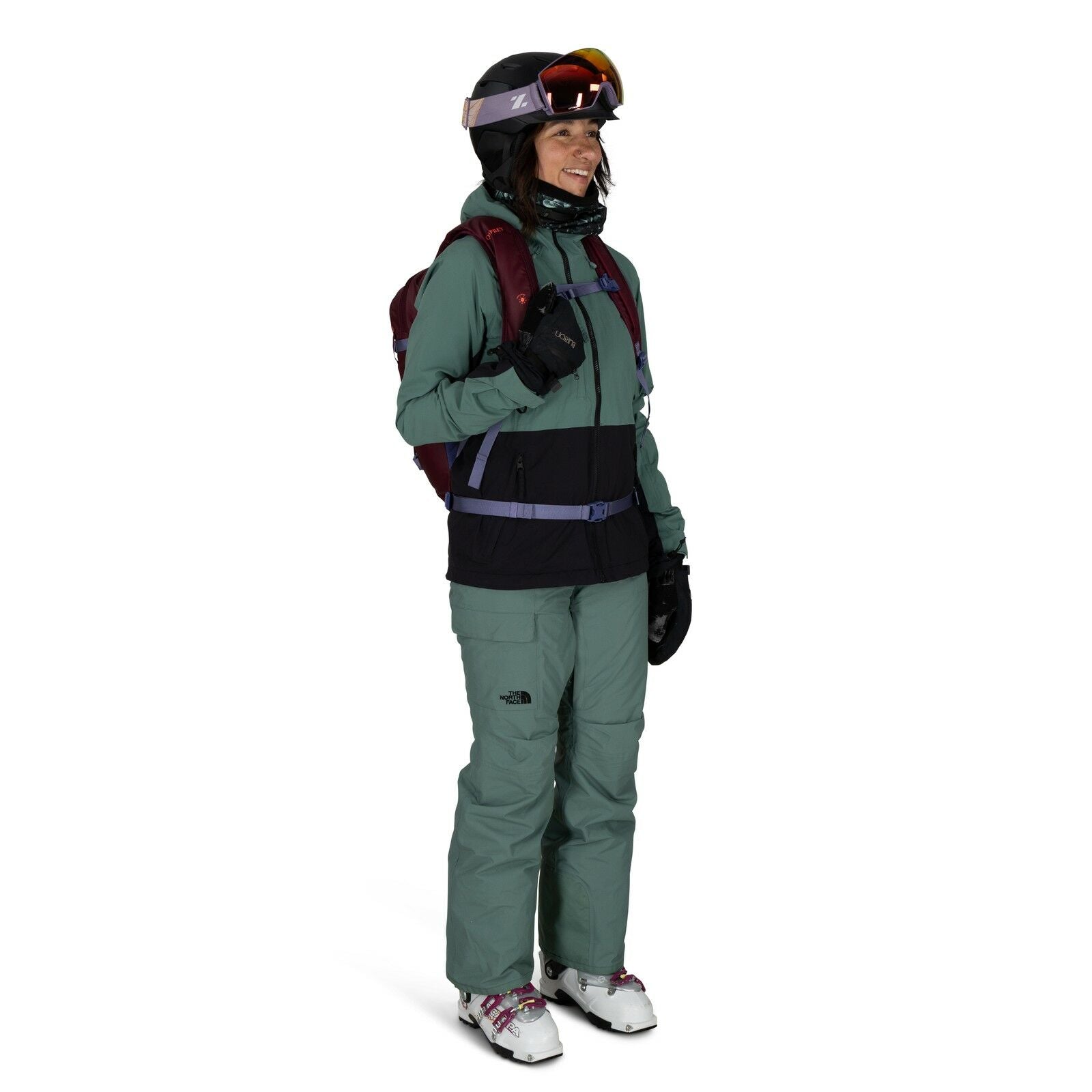 The image features a person dressed in winter sports attire, suitable for skiing or snowboarding. They are wearing a green jacket with black detailing and matching green pants, both featuring the North Face logo. The individual is equipped with a red back