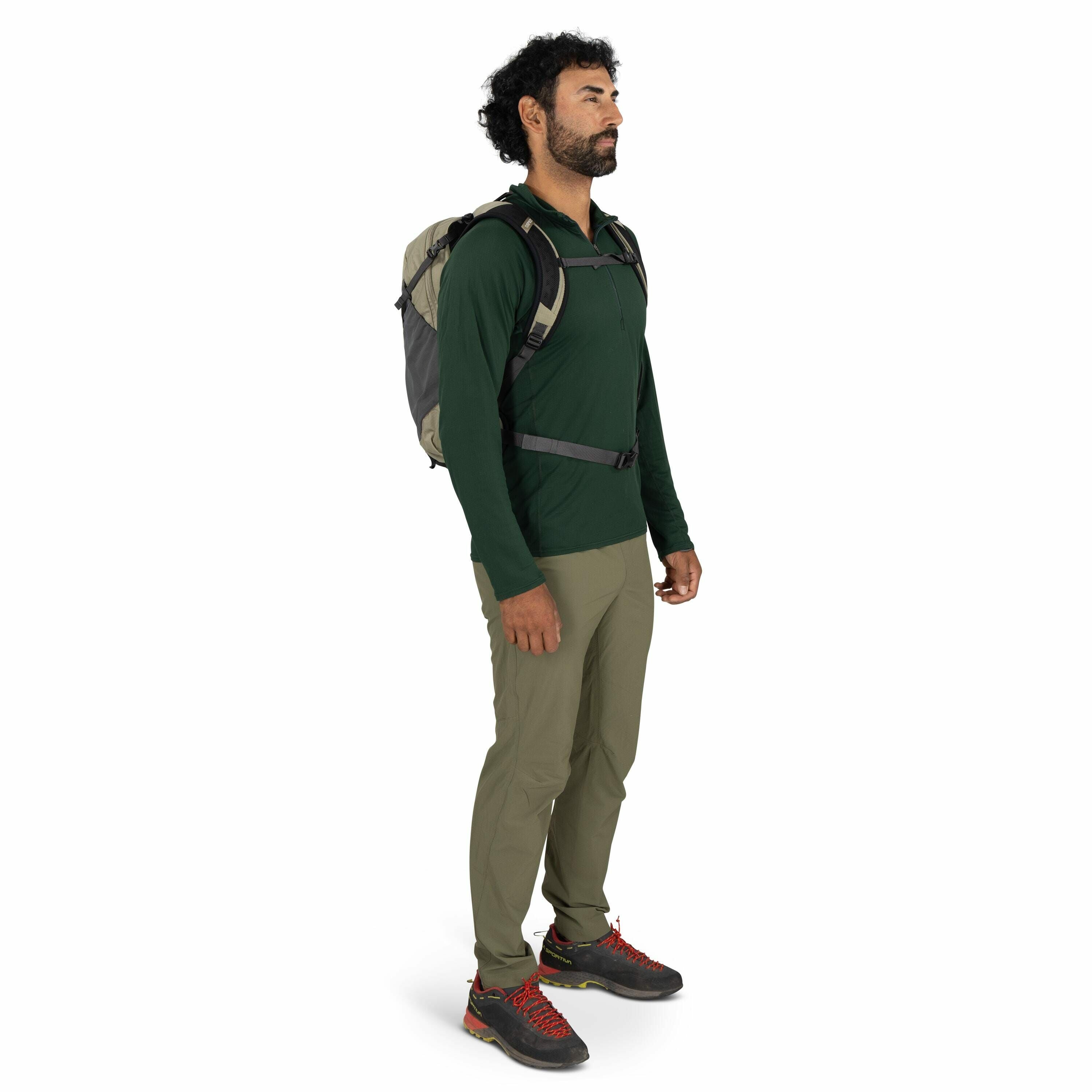 The image shows a person dressed in outdoor hiking attire. They are wearing a dark green long-sleeve shirt and khaki-colored pants, which appear to be suitable for trekking or hiking activities. The person has on a pair of black hiking shoes with bright r