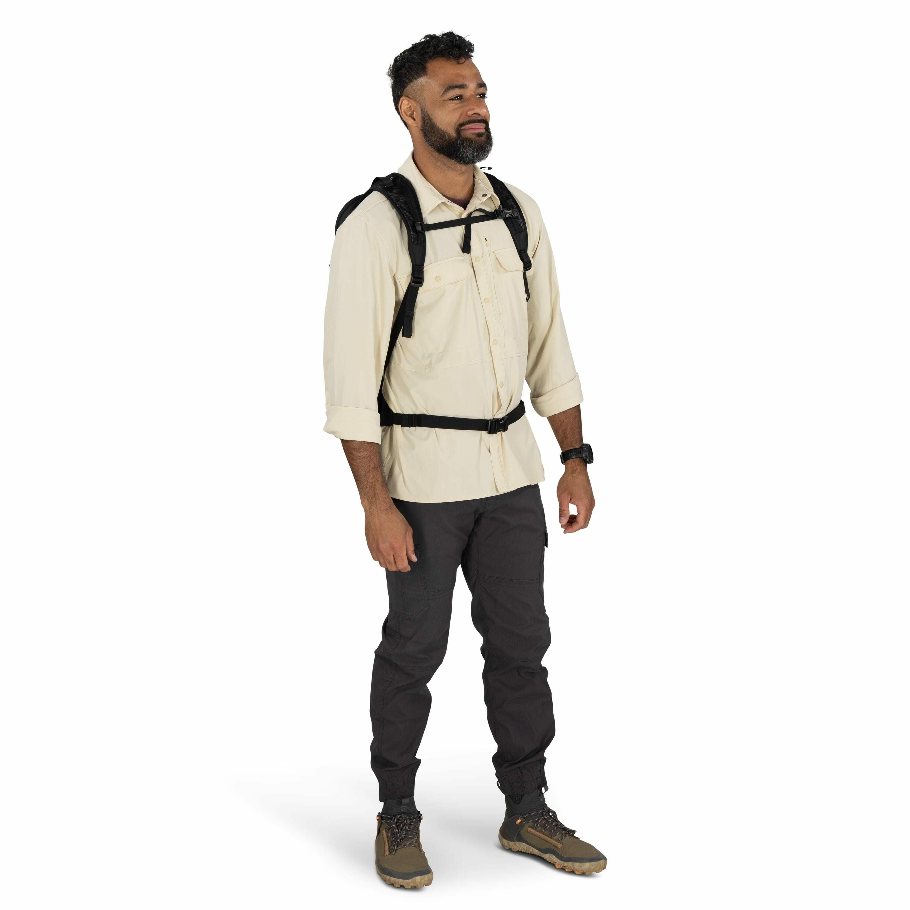 The image features a person dressed in outdoor or hiking attire. They are wearing a long-sleeved, beige button-up shirt and dark grey cargo pants with cuffs near the ankles. On their feet are rugged hiking shoes, suitable for outdoor activities. The perso