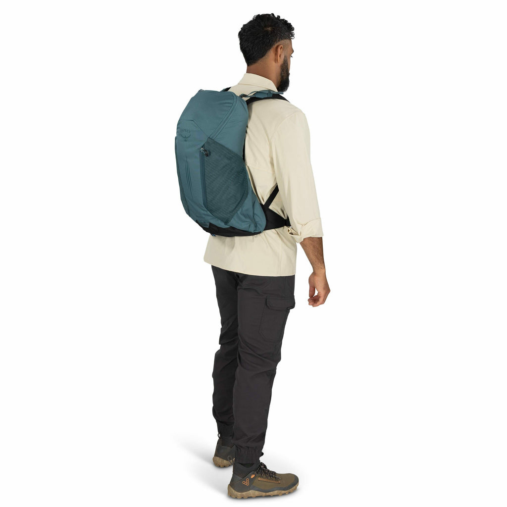 The image shows a person standing and wearing outdoor clothing suitable for hiking or trekking. The individual has on a beige long-sleeved shirt, which is paired with dark cargo pants. On their feet, they are wearing sturdy brown hiking boots. They have a