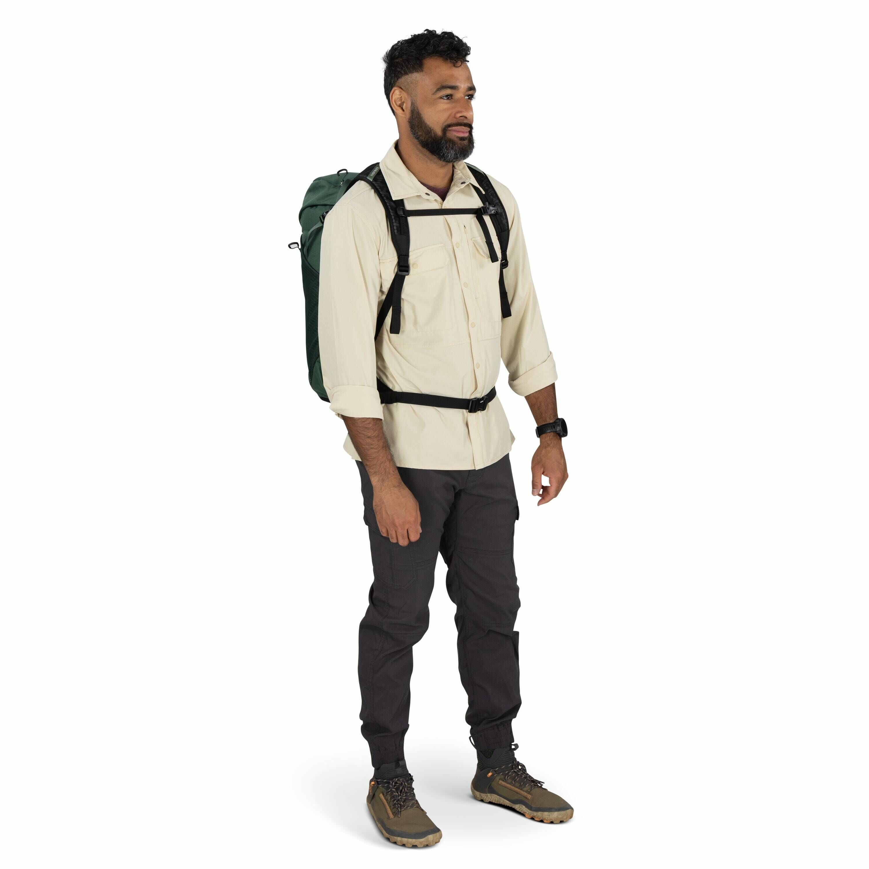 The image features a man dressed in outdoor gear, suggesting he is prepared for a hiking or camping excursion. He is wearing a light-colored, long-sleeved shirt with the sleeves rolled up, paired with dark cargo pants and outdoor shoes designed for rough