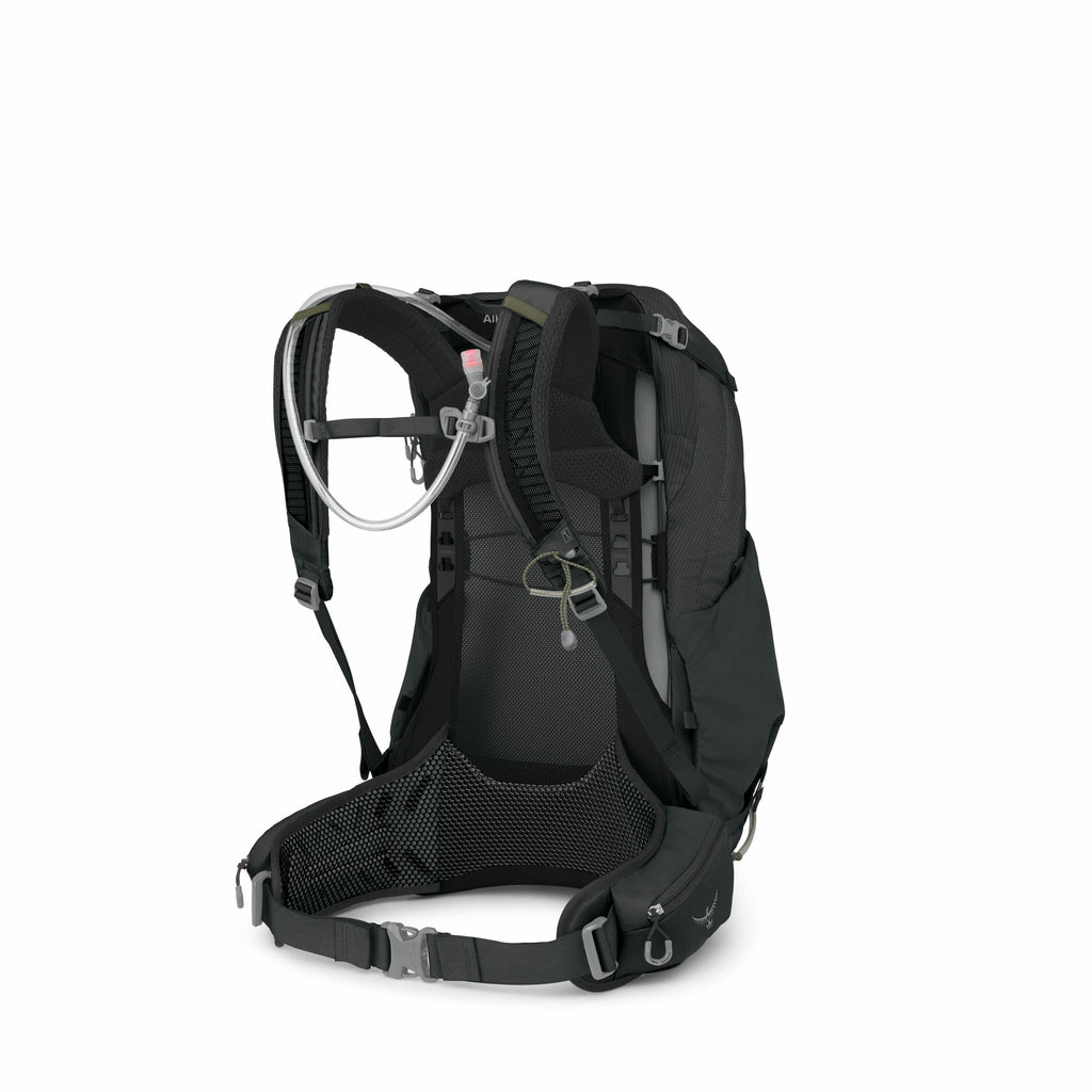 The image features a high-performance black hiking or backpacking backpack, viewed from the side that would rest against the wearer's back. It is equipped with a hydration system, as indicated by the tube with a pink nozzle attached to one of the shoulder