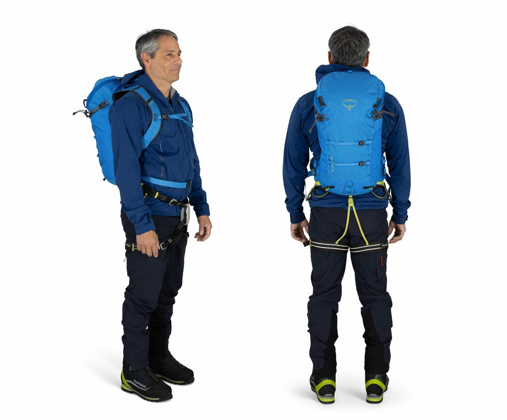 The image shows a man dressed in hiking or outdoor gear, captured from both front and back views. He is wearing a bright blue jacket with matching blue backpack, and the backpack features a sleek, compact design with multiple securing straps. The outfit i