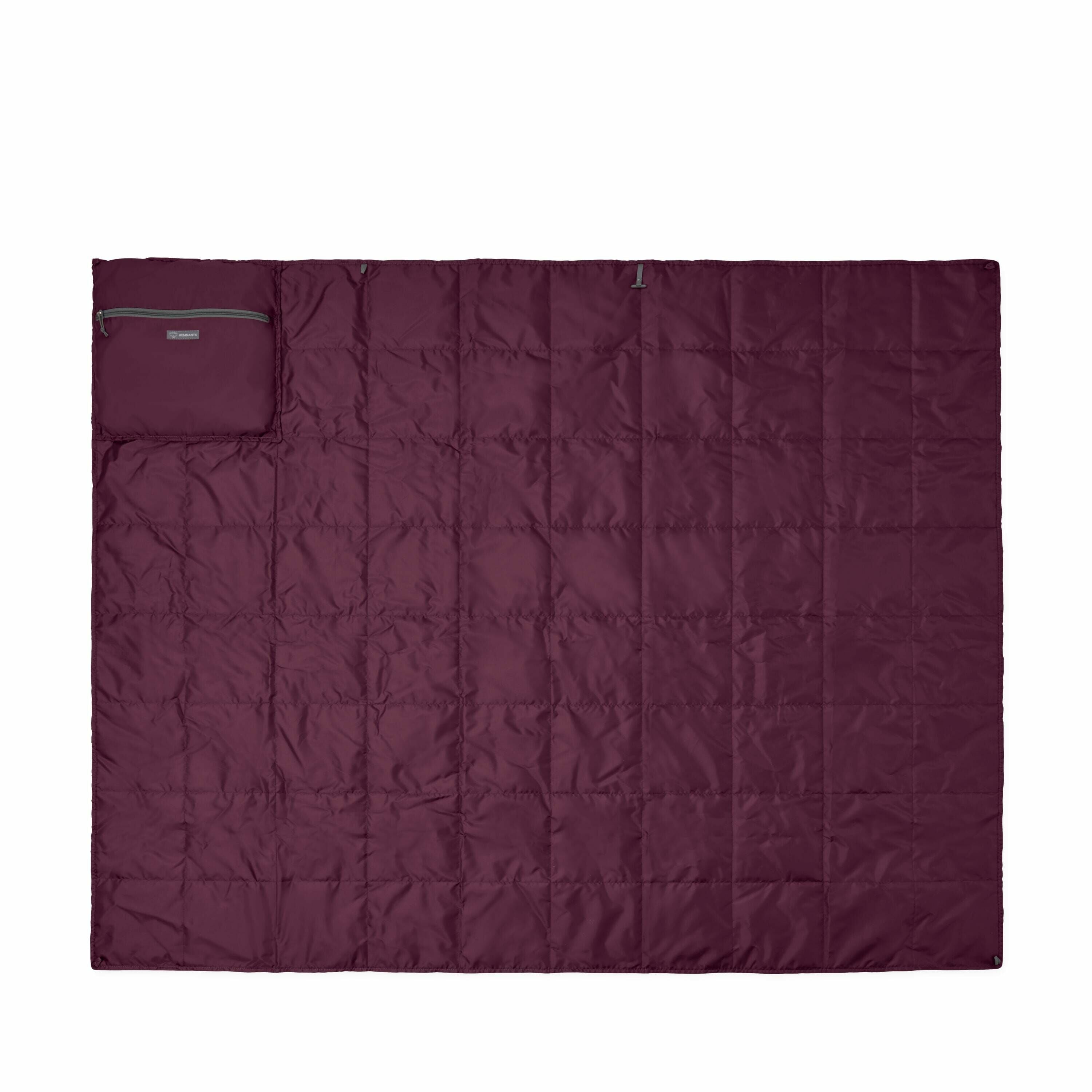 The image shows a maroon-colored quilt laid out flat, appearing as a large rectangular piece with a grid pattern. In the top left corner, there is a small pocket or pouch made of the same material, which seems to be sewn into the quilt. The quilt appears