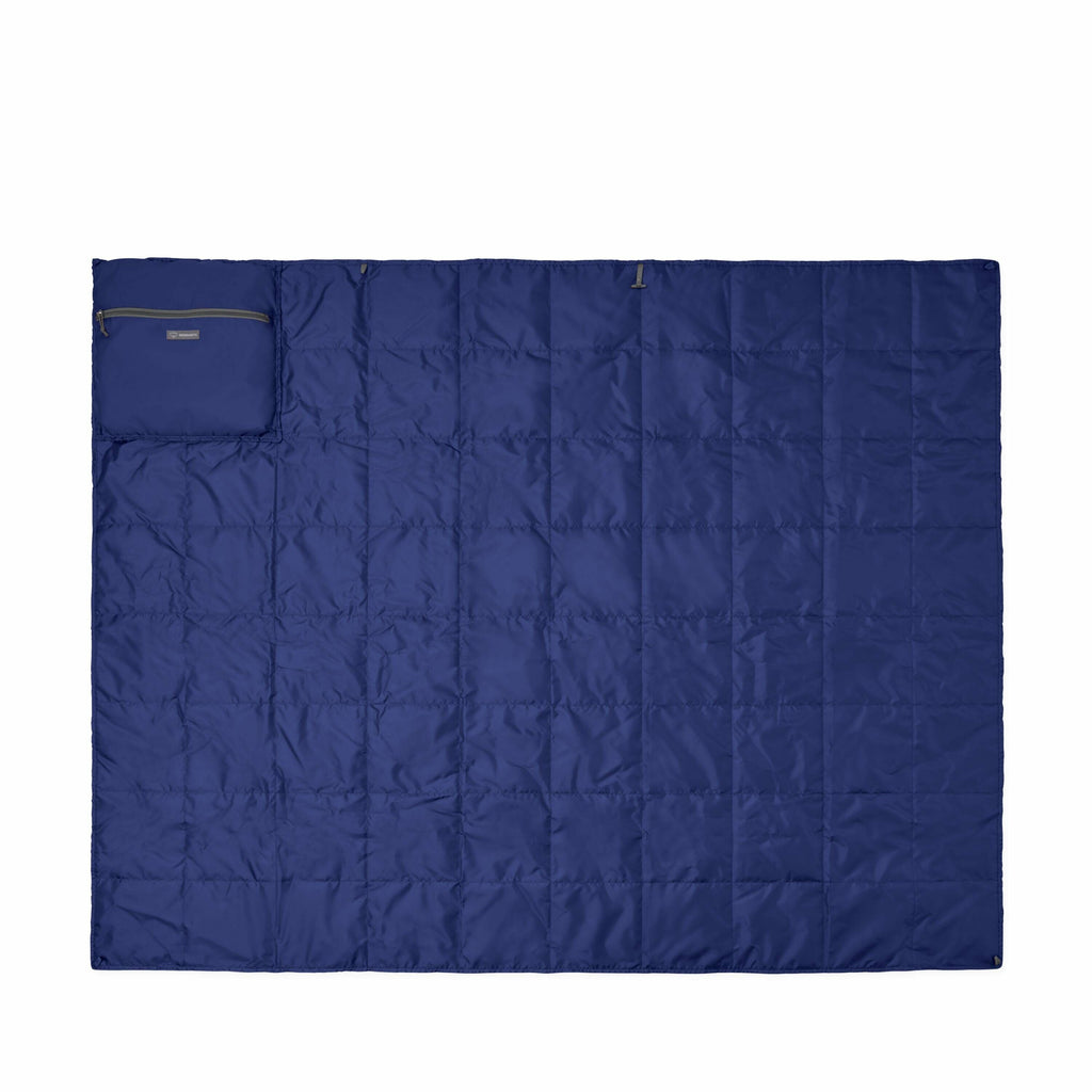 The image showcases a blue quilted blanket laid out flat, with a pocket or pouch situated in the top left corner. The blanket appears to have a smooth, shiny texture, likely made from a synthetic material such as nylon or polyester, providing a lightweigh