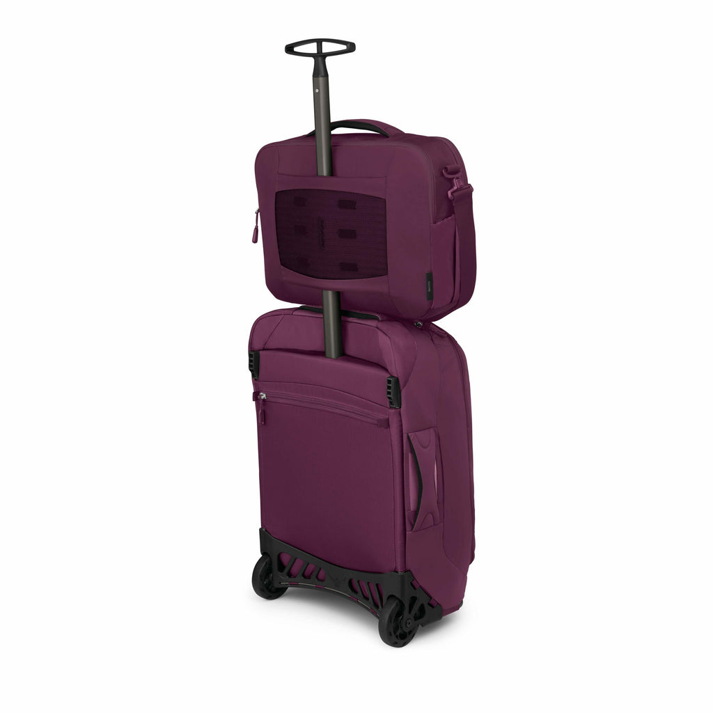 The image shows a maroon travel suitcase with a smaller bag attached on top, designed for convenience and easy transport. The suitcase has a retractable handle and two wheels at the bottom, which suggests it's meant for rolling. The smaller bag on top app