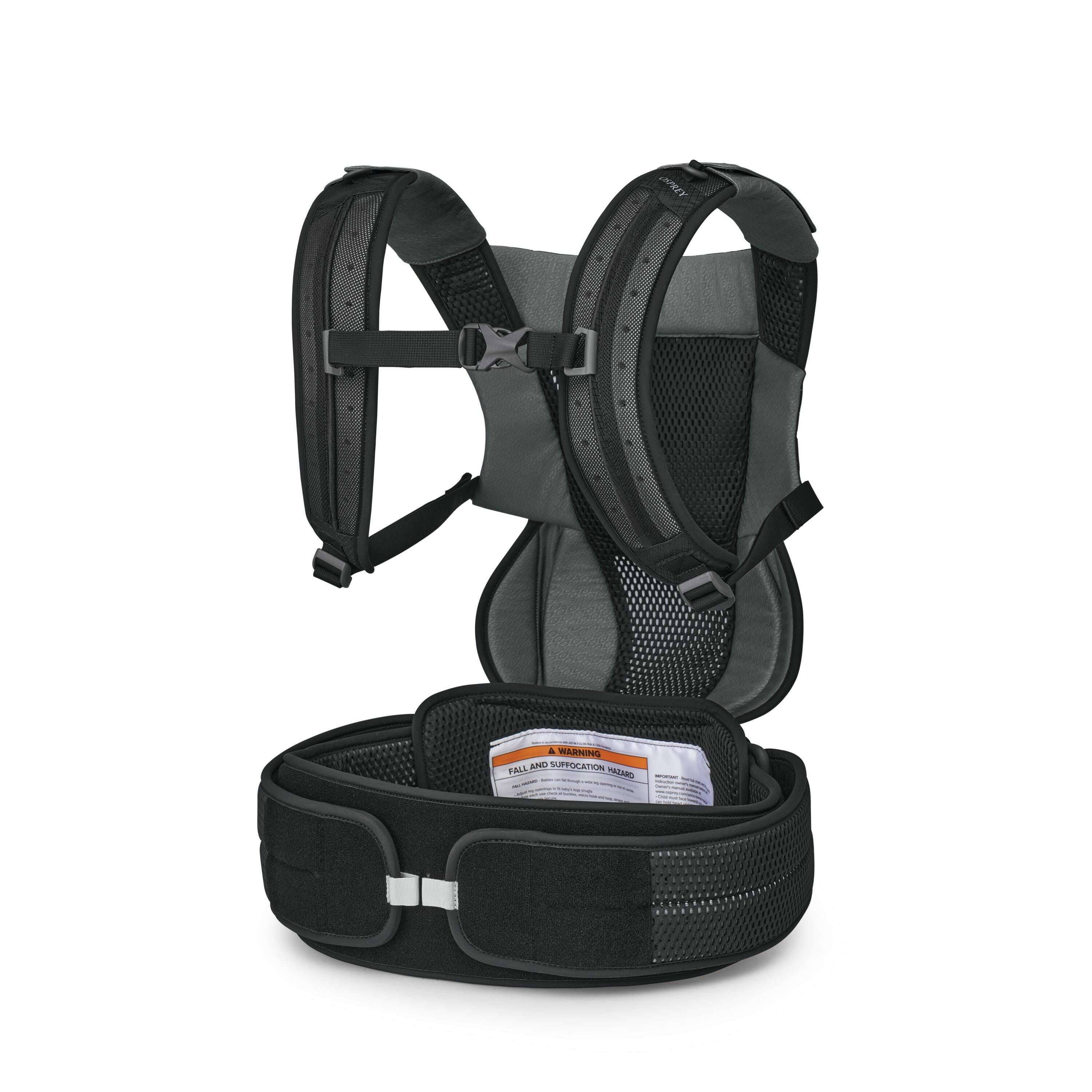 The images depict a baby carrier harness with a backpack-like design. The harness is primarily black with grey accents and features padded shoulder straps with adjustable buckles for comfort and fit. A prominent safety warning label is visible on the fron