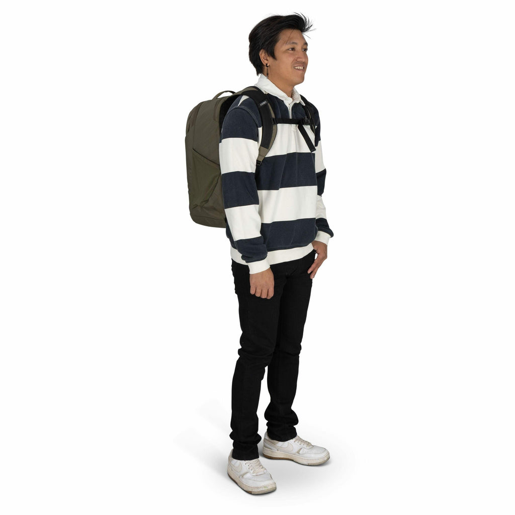 The image shows a person standing and wearing a casual outfit, which consists of a long-sleeve rugby-style shirt with broad horizontal stripes in white and dark blue. The individual is also wearing black pants and white sneakers with visible wear. They ar