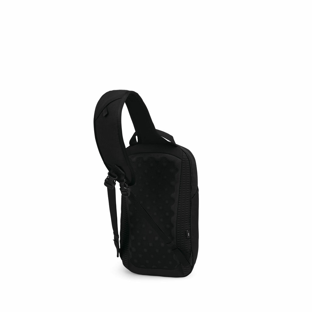The image shows a sleek, black sling backpack designed for modern convenience and style. The backpack features a single, adjustable shoulder strap that is well-padded for comfort. The back of the bag has a textured, dotted pattern that likely provides add