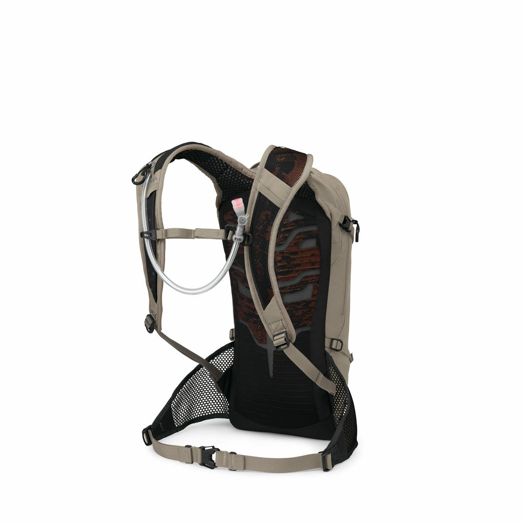 The image displays a backpack designed with a hydration system, evidenced by the visible transparent tube with a pink mouthpiece attached to it. The backpack features a combination of beige, black, and red colors, with a distinct patterned mesh on the bac
