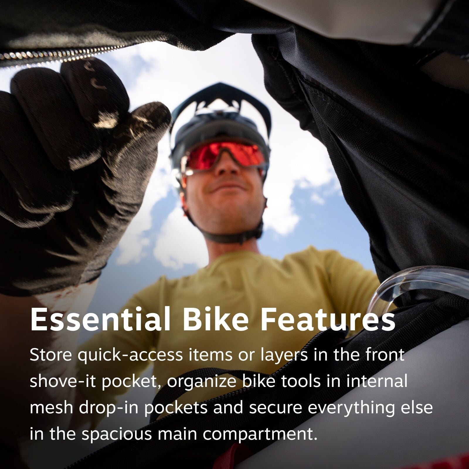 The image features a person wearing a yellow shirt and a black bicycle helmet, looking down as though they are about to zip up a bag. The scene is framed from the perspective of inside the bag, with the person's gloved hand poised near the open zipper. Th