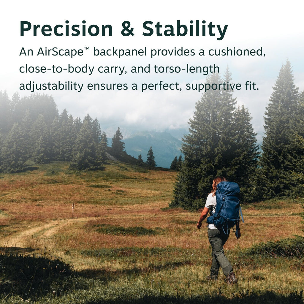 The image shows a scenic landscape with a person hiking through a grassy field surrounded by lush evergreen trees. The hiker is carrying a large, blue backpack and walking towards the right, away from the viewer, suggesting a journey or adventure. The sky