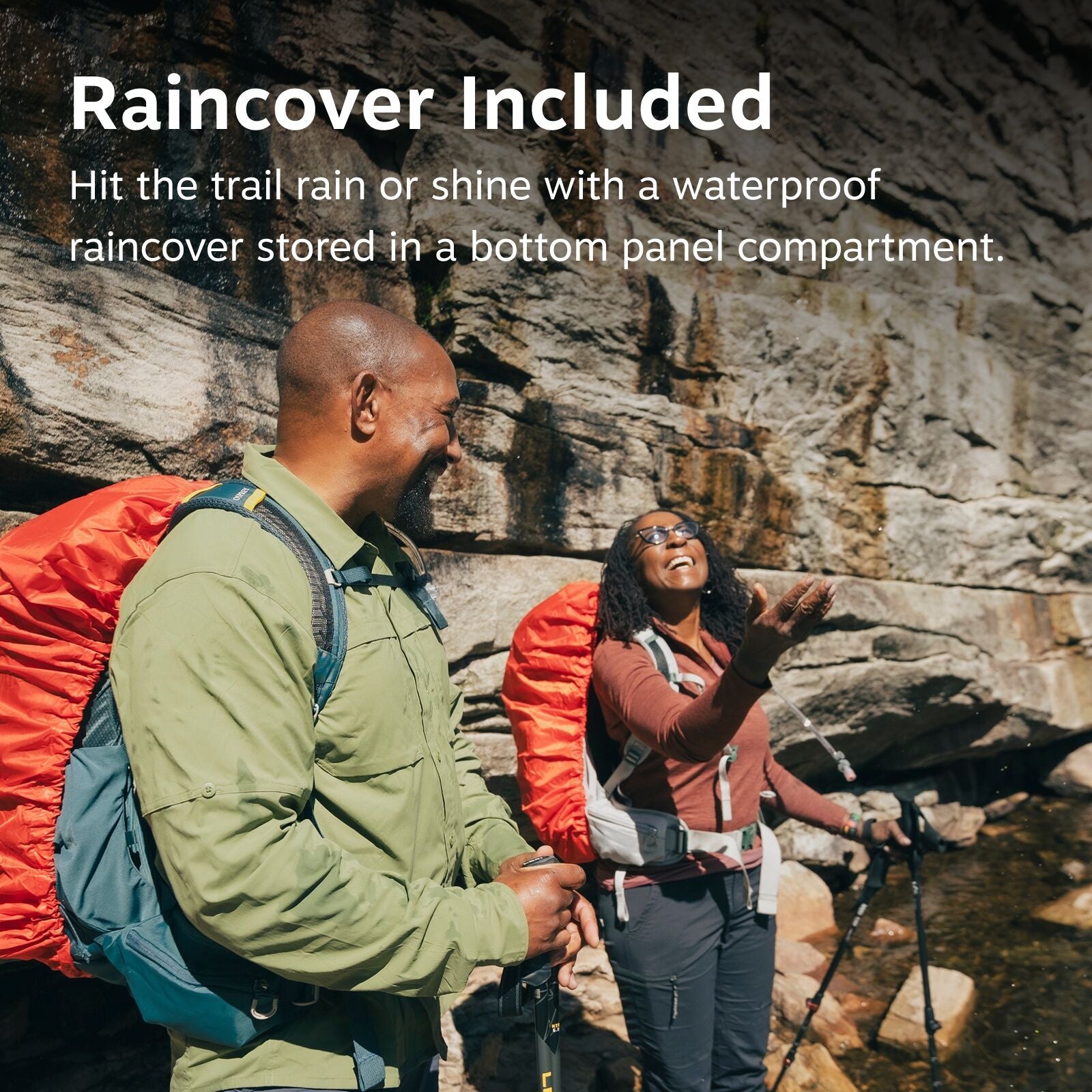 The image depicts two hikers standing in front of a rocky cliff, equipped with hiking gear, including trekking poles and backpacks covered with bright orange raincovers. The foreground hiker is wearing a light green jacket and has a dark gray backpack wit