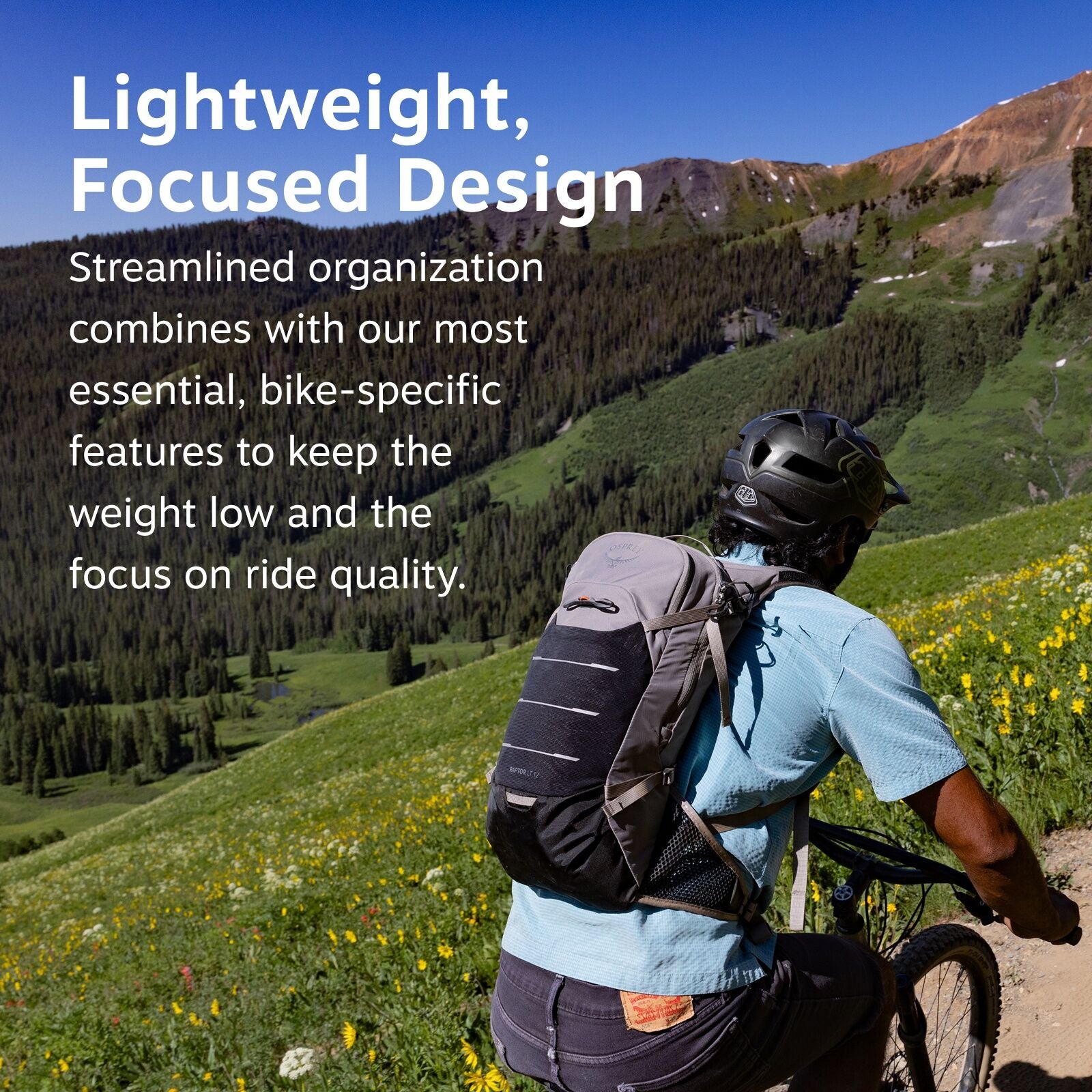 The image features a cyclist riding through a lush, mountainous terrain covered in vibrant green grass and yellow wildflowers. The person is wearing a blue shirt and a black helmet, and they have a grey and black Osprey backpack with visible branding on t