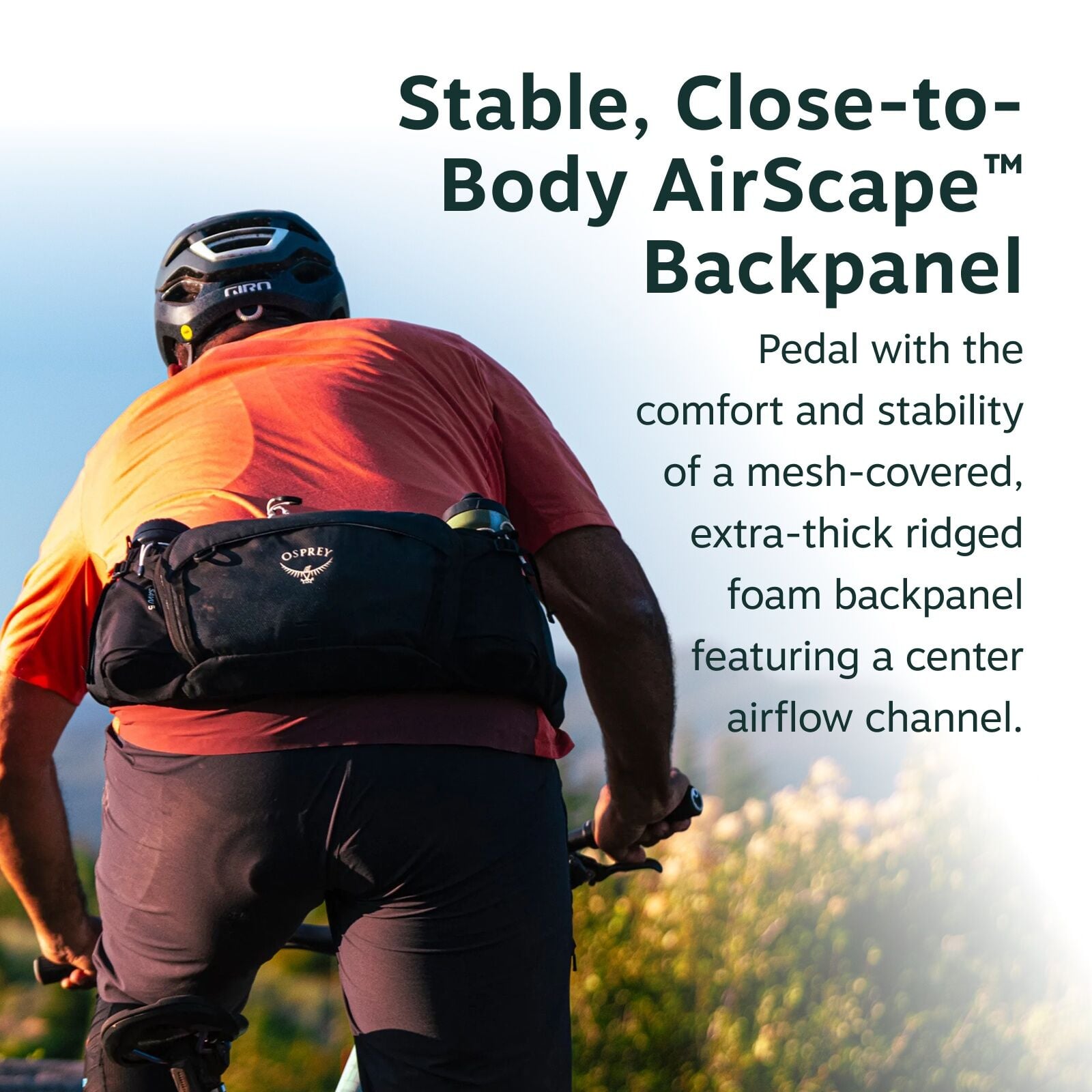 The image features a cyclist from behind, riding a bicycle along a trail surrounded by green bushes and grass. The cyclist is wearing a red shirt, black pants, and a helmet, and has an Osprey brand pack strapped around their lower back. The background sho
