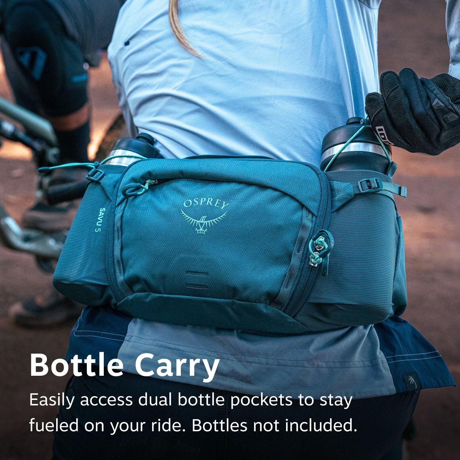 The image shows an individual wearing an Osprey waist pack designed for cyclists. The pack is teal in color and features dual bottle pockets, each holding a water bottle, allowing for easy access during a ride. The Osprey logo is prominently displayed on