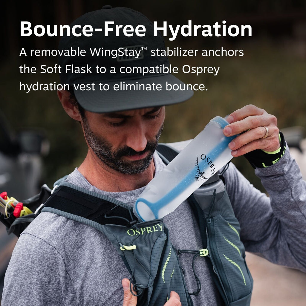 The image features an individual wearing a gray hydration vest by Osprey, which is specifically designed to provide bounce-free hydration. The vest has several pockets and straps, with the Osprey logo prominently displayed on it. The person is holding an