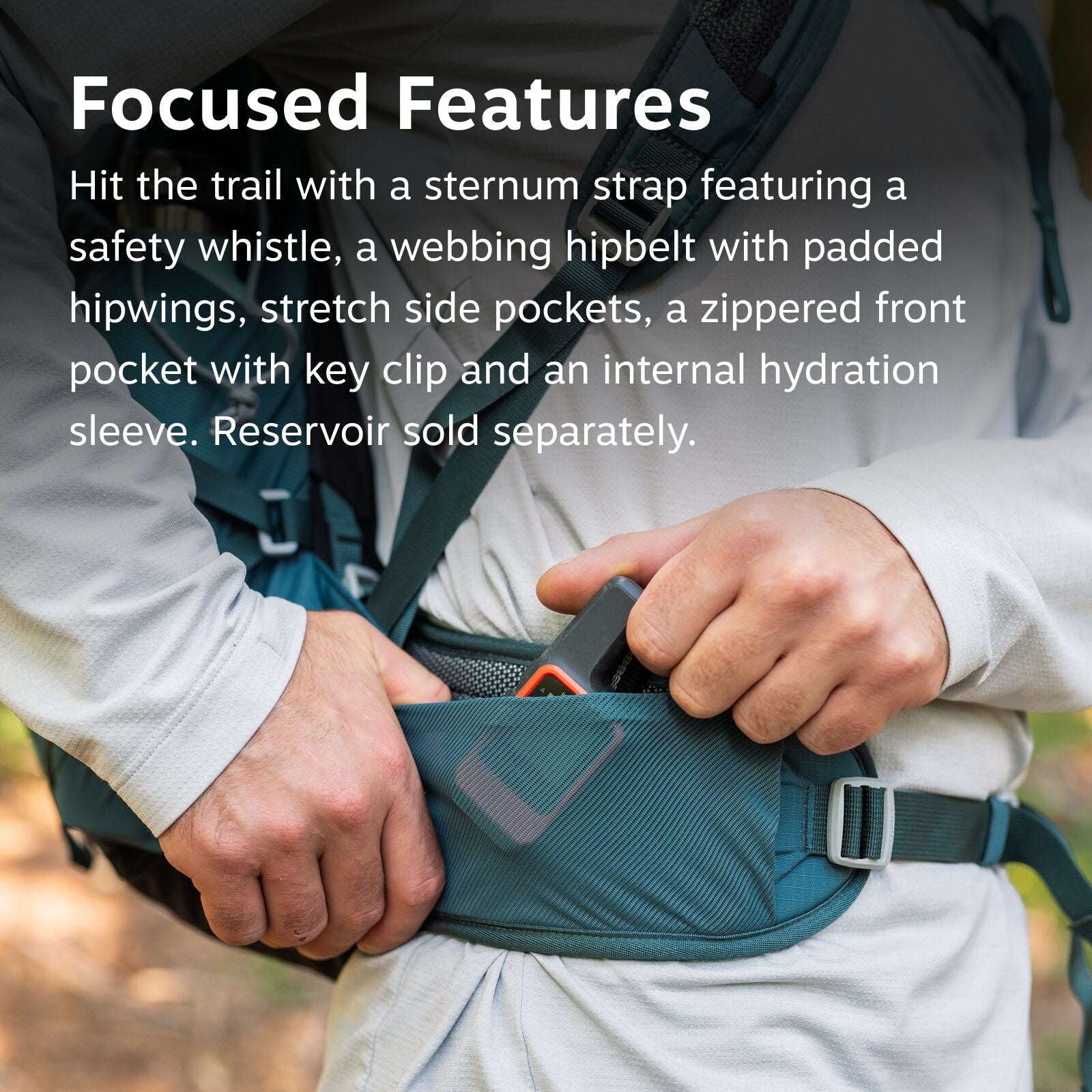 The image features a close-up of a person adjusting a hiking backpack's hipbelt. The hipbelt is teal and appears padded, with a small pocket that contains a multi-tool or similar item. The person is wearing a long-sleeve light gray shirt and is standing i
