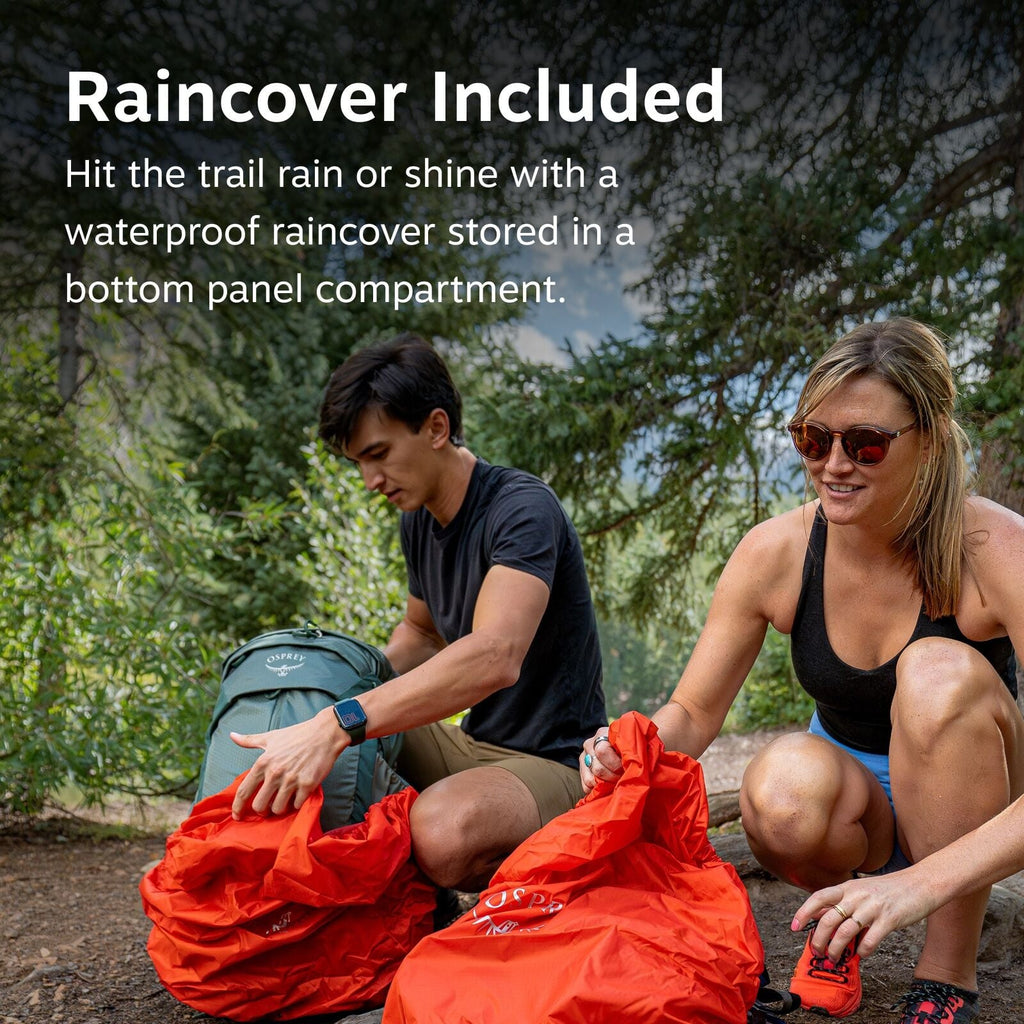 The image shows two people outdoors in a wooded area, engaging in an activity related to hiking or camping. The person on the left is holding a green Osprey backpack, from which they are removing or preparing to place an orange rain cover. The person on t