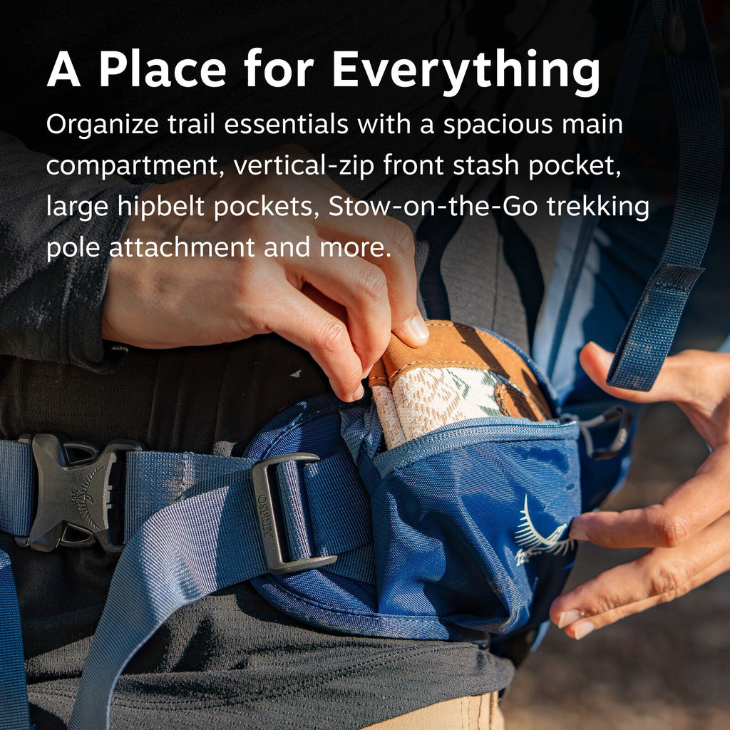 The image shows a close-up of a person accessing a pocket on a blue hiking backpack. The person is pulling out a small, floral-patterned notebook from the hip belt pocket of the backpack, which has the Osprey logo visible on it. The backpack features a bu